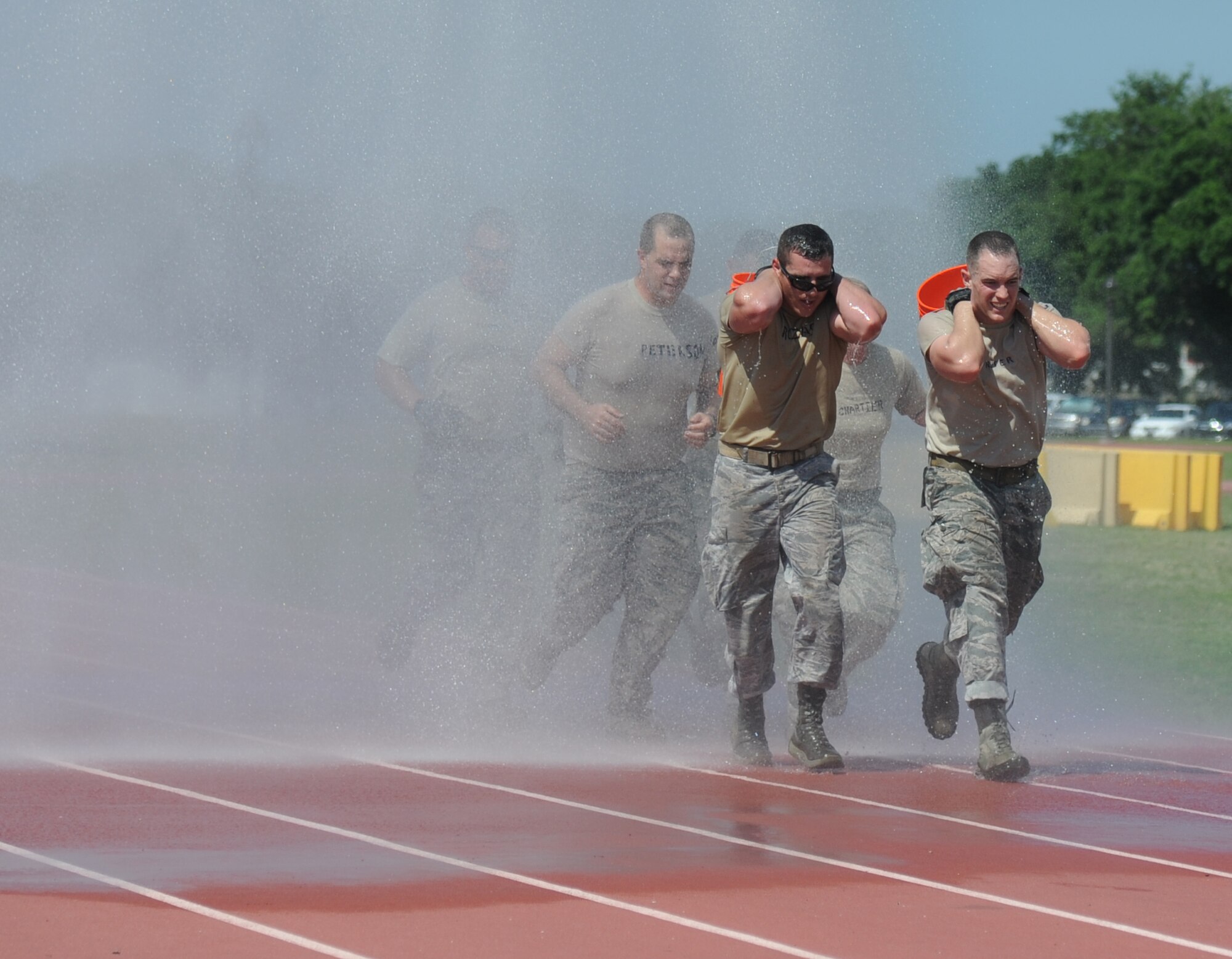Ricky & The Bayonets team members, Senior Airman Kevin Rozas and Staff Sgt. Dayton Riter, from the 81st Security Forces Squadron lead their team through a water shower as they complete the “Mogadishu Mile,” which is a one-mile run while carrying buckets of sandbags, during the 81st Training Wing Warrior Challenge hosted by the 81st Mission Support Group June 6, 2014, at the Triangle Track, Keesler Air Force Base, Miss.  The Warrior Challenge event was held in memory of the 70th anniversary of The Normandy Invasion also known as D-Day.  It consisted of nine six-member teams racing in a competition designed to take them through various aspects of a deployment. Ricky & The Bayonets placed first in the competition. (U.S. Air Force photo by Kemberly Groue)