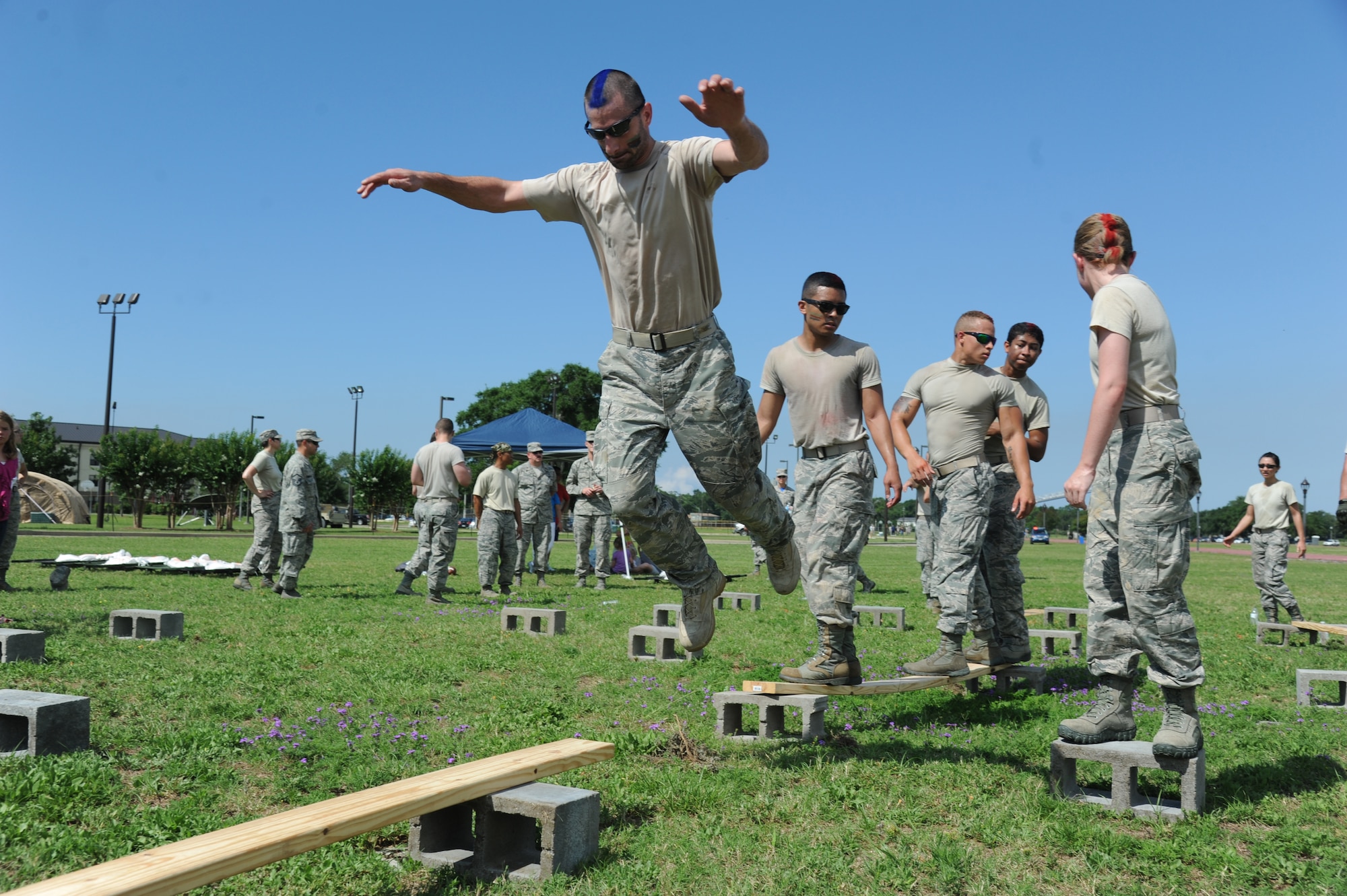 Staff Sgt. Daniel Storm leads his team, The Logistics Readiness Squadron Warriors, through the “’X’ Factor” challenge during the 81st Training Wing Warrior Challenge hosted by the 81st Mission Support Group June 6, 2014, at the Triangle Track, Keesler Air Force Base, Miss. The challenge consists of using the whole team to work their way through a maze using only cinderblocks and various length pieces of wood without touching the ground. The Warrior Challenge event was held in memory of the 70th anniversary of The Normandy Invasion also known as D-Day.  It consisted of nine six-member teams racing in a competition designed to take them through various aspects of a deployment. (U.S. Air Force photo by Kemberly Groue)
