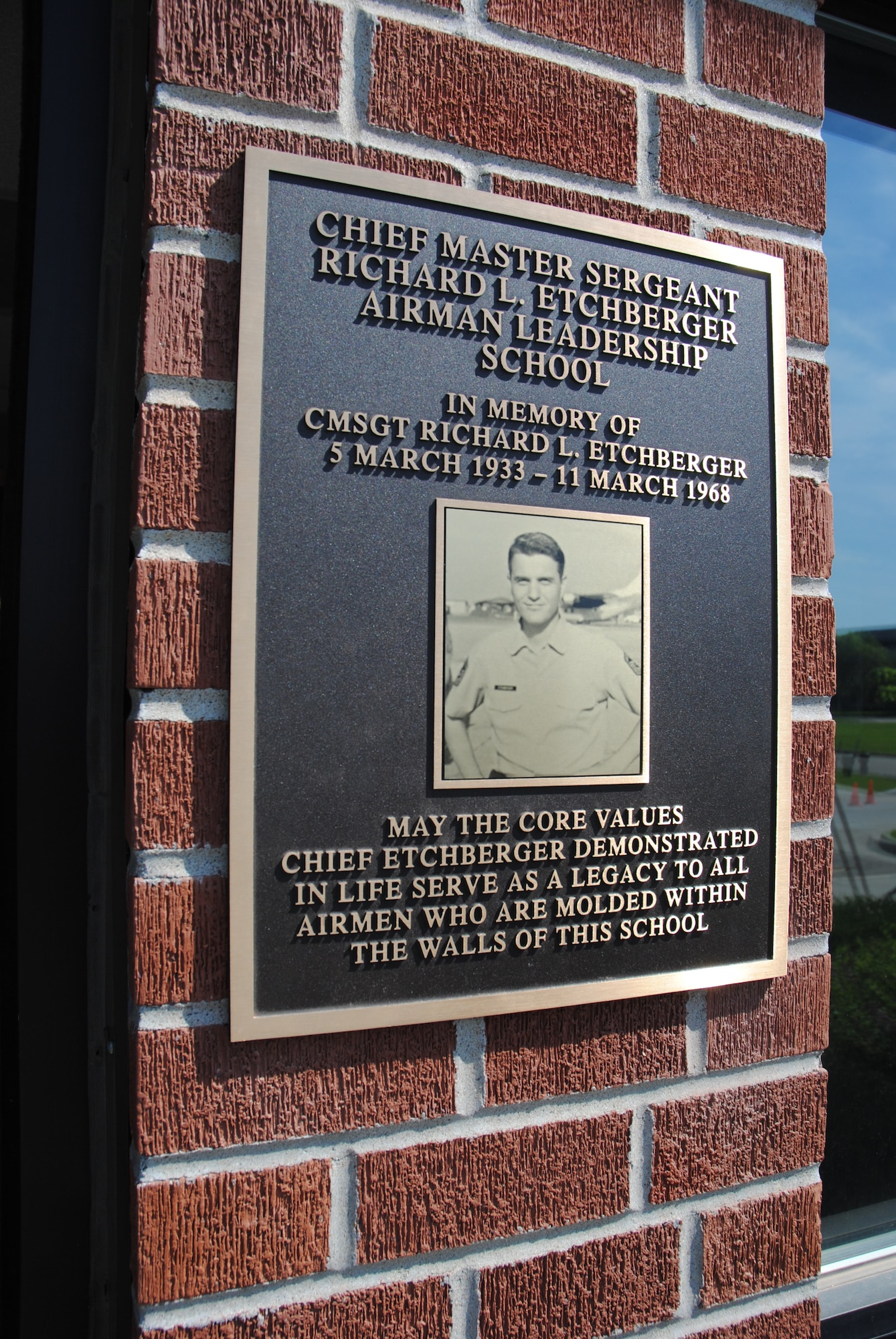 A golden plague with the image of Chief Etchberger shines much bright being recently unveiled during the Chief Master Sgt. Richard L. Etchberger Airman Leadership School building dedication ceremony held June 4, 2014, on Grand Forks Air Force Base, N.D. The lower part of the inscription reads, "May the core values Chief Etchberger demonstrated in life serve as a legacy to all Airmen who are molded within the walls of this school." (U.S. Air Force photo/Staff Sgt. Luis Loza Gutierrez) 
