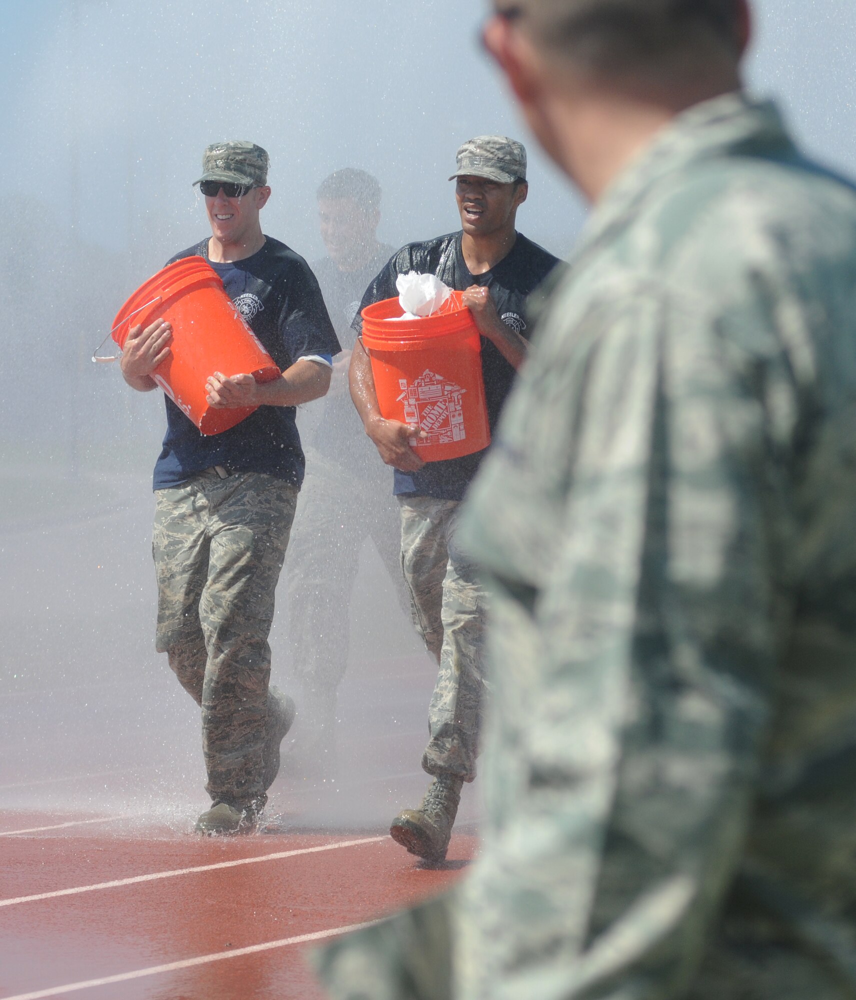The Fire Department team members, Master Sgt. Walter Shutler, Keesler Firefighter, and Tech. Sgt. Waymon Brown, 81st Force Support Squadron, lead their team through a water shower as they complete the “Mogadishu Mile,” which is a one-mile run while carrying buckets of sandbags, during the 81st Training Wing Warrior Challenge hosted by the 81st Mission Support Group June 6, 2014, at the Triangle Track, Keesler Air Force Base, Miss.  The event was held in memory of the 70th anniversary of The Normandy Invasion also known as D-Day.  It consisted of nine six-member teams racing in a competition designed to take them through various aspects of a deployment.  (U.S. Air Force photo by Kemberly Groue)