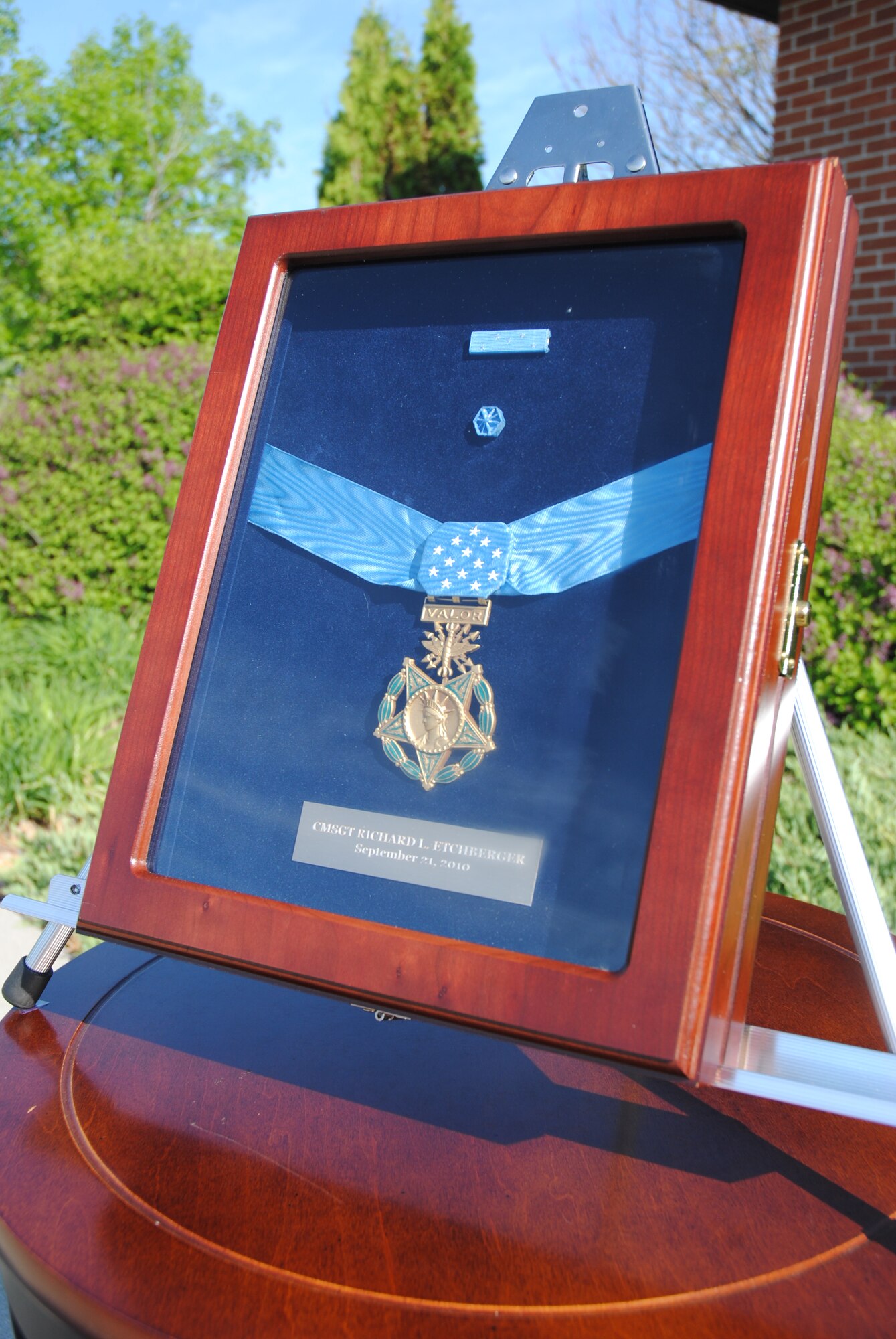 The sun shines bright on the encased Medal of Honor of Chief Master Sgt. Richard L. Etchberger as it sits on display in front of the airman leadership school June 4, 2014, on Grand Forks Air Force Base, N.D. The nation’s highest military honor was posthumously awarded to Chief Etchberger on Sept. 10, 2010, in recognition of his sacrifice and heroic actions in March 1968. Etchberger's Medal of Honor is extraordinary on another count: it is the first Medal of Honor to an individual serving in the highest enlisted grade in any service. No other person in the pay grade of E-9 has been awarded the decoration while serving as a sergeant major (Army and Marine Corps), master chief petty officer (Navy), master gunnery sergeant (Marine Corps) or chief master sergeant (Air Force).  (U.S. Air Force photo/Staff Sgt. Luis Loza Gutierrez) 
