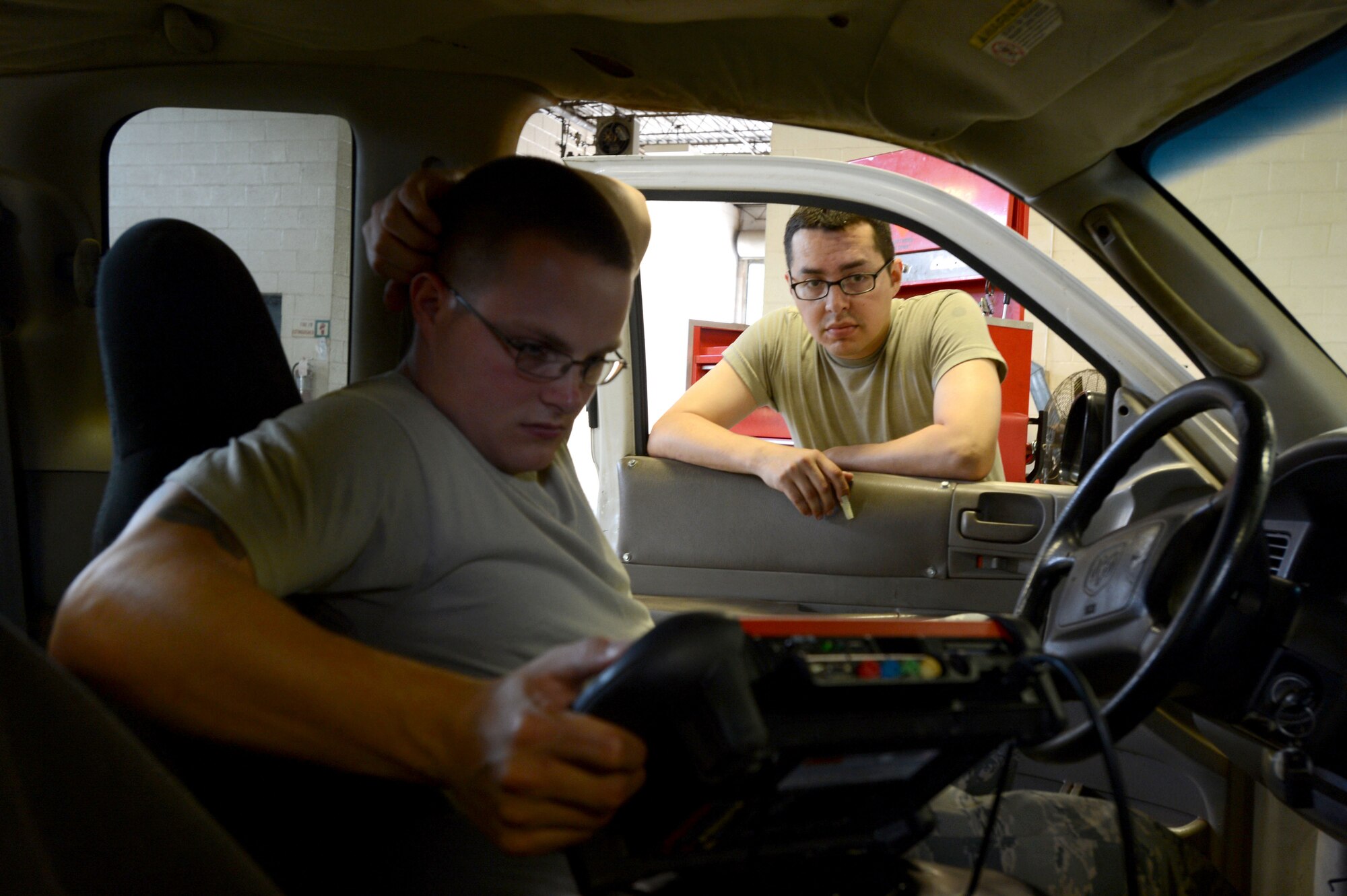 [From left] U.S. Air Force Senior Airmen Dexter Tapley and Patrick Sanchez, 20th Logistics Readiness Squadron vehicle maintenance journeymen, use a computer diagnostics device to determine a truck's cause of engine failure at Shaw Air Force Base, S.C., June 04, 2014. Tapley and Sanchez worked for several hours trying to figure out the cause for engine failure, the truck has been worked on several times before. (U.S. Air Force photo by Airman 1st Class Jensen Stidham/Released)
