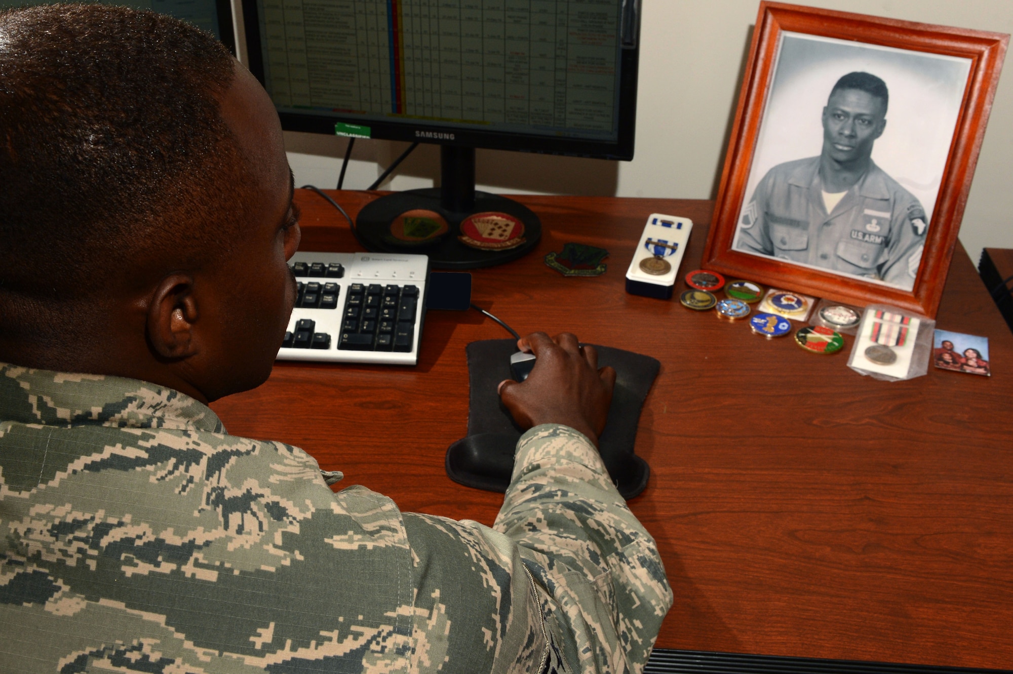 U.S. Air Force Senior Airman Tyler Roberts, 20th Maintenance Operations Squadron time compliance technical order manager, looks at a picture of his grandfather which is displayed on his desk at Shaw Air Force Base, S.C., June 5, 2014. Roberts said he is inspired by his grandfather, retired U.S. Army Sgt. 1st Class Roberts, and that the picture keeps him motivated throughout each day. (U.S. Air Force photo by Airman 1st Class Jensen Stidham/Released)