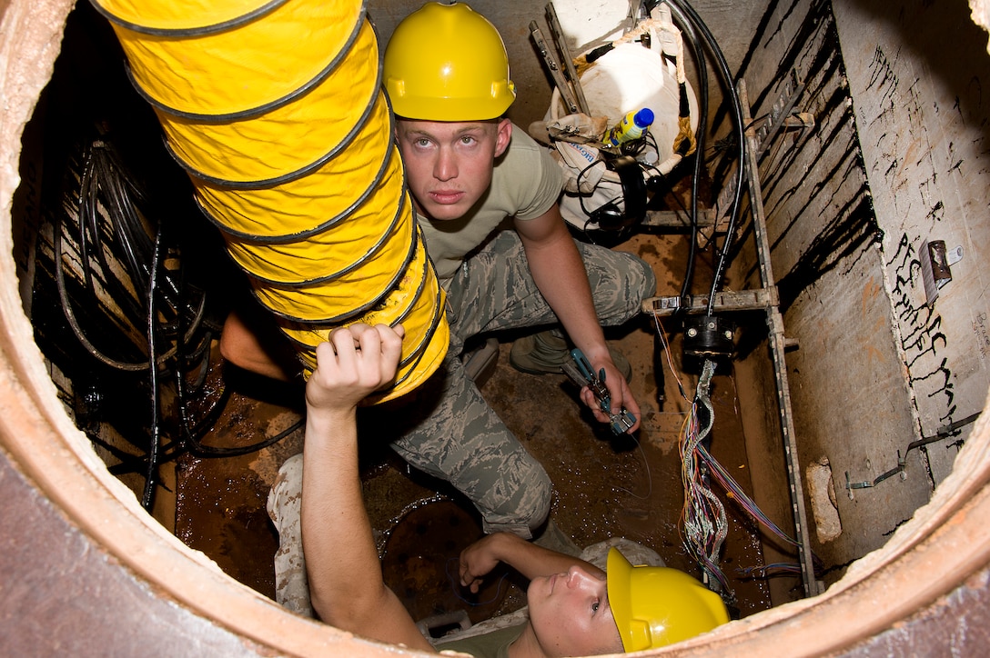 Student Lance Cpl. Brandon Eto and Airmen 1ST Class Kyle Willett, 364TH Training Wing Squadron, adjust the air flow as they prepares to replace an old faulty 25 pair telecommunication cable with new cable in an underground environment June 5, 2014. Students ensure safe environment by setting up all safety devices, testing underground environment for any unsafe conditions, removing splice closure, splicing in new cable, removing old cable, testing new cable, and reinstalling splice closure. (U.S. Air Force photo by Danny Webb/Released)