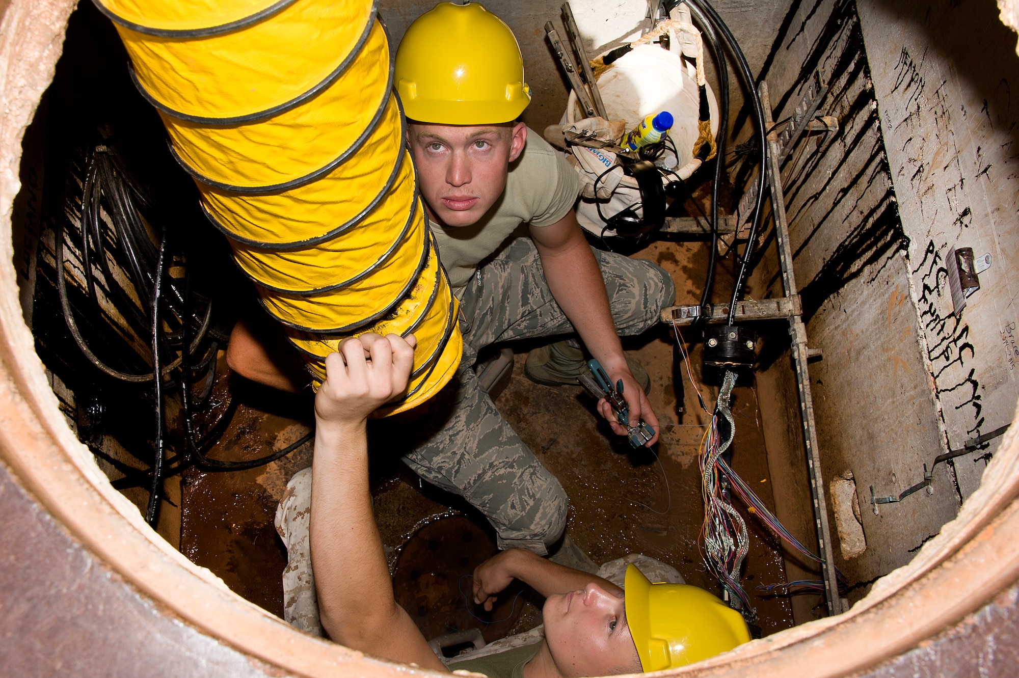 Student Lance Cpl. Brandon Eto and Airmen 1ST Class Kyle Willett, 364TH Training Wing Squadron, adjust the air flow as they prepares to replace an old faulty 25 pair telecommunication cable with new cable in an underground environment June 5, 2014. Students ensure safe environment by setting up all safety devices, testing underground environment for any unsafe conditions, removing splice closure, splicing in new cable, removing old cable, testing new cable, and reinstalling splice closure. (U.S. Air Force photo by Danny Webb/Released)