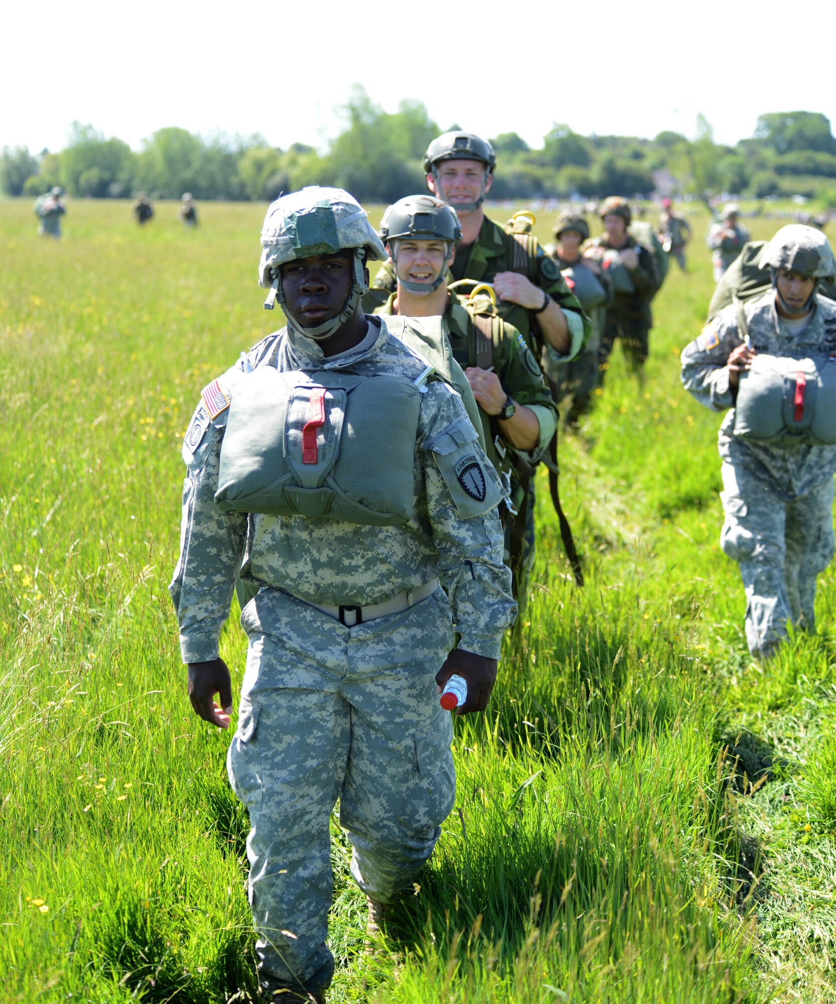 A procession of parachutists walk off the Iron Mike Drop Zone outside St. Mere Eglise, France after completing a static-line jump during the 70th anniversary celebration of D-Day June 8, 2014. The jumps commemorated the 70th anniversary of Operation Overlord, the D-Day invasion of World War II. (U.S. Air Force photo/Airman 1st Class Dillon Johnston/Released)