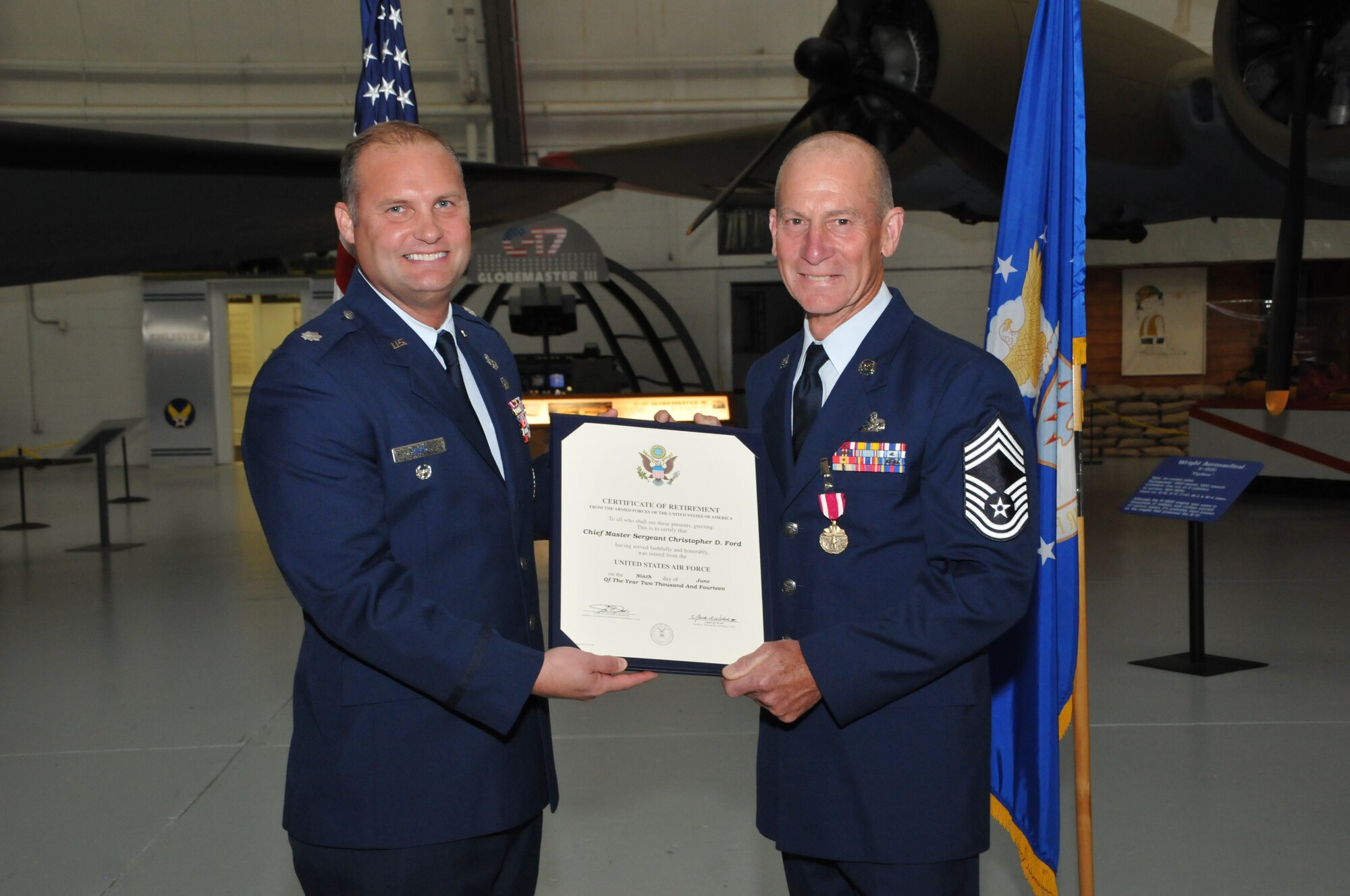 Lt. Col. Thomas Kerr (left), Joint Logistics Operations Center battle captain and former 512th Maintenance Squadron commander, presents the Certificate of Retirement to Chief Master Sgt. Christopher Ford, the outgoing 512th MXS superintendent, during a ceremony June 7, 2014 at the Air Mobility Command Museum, Dover, Del. Ford retired, effective June 9, after serving more than 36 years in a variety of positions as an Air Force active-duty member, reservist and civilian employee with the 436th and 512th airlift wings. (U.S. Air Force photo/Senior Airman Joe Yanik)