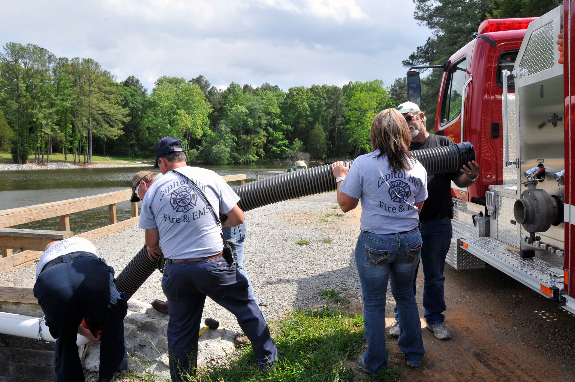 Members of the Capitol Hill and Arnold Air Force Base fire departments work together to perform a first draft of the dry hydrant installed at Morris Ferry Dock. Pictured in the first photo are Capitol Hill fire personnel hooking the fire truck up to the dry hydrant. As seen in the second photo, the fire hose successfully sprays water from the lake. Pictured in the last photo are AEDC fire personnel Odell Crutchfield (left) and Billy King (right) assisting in detaching equipment from the truck. (Photos by Jacqueline Cowan)