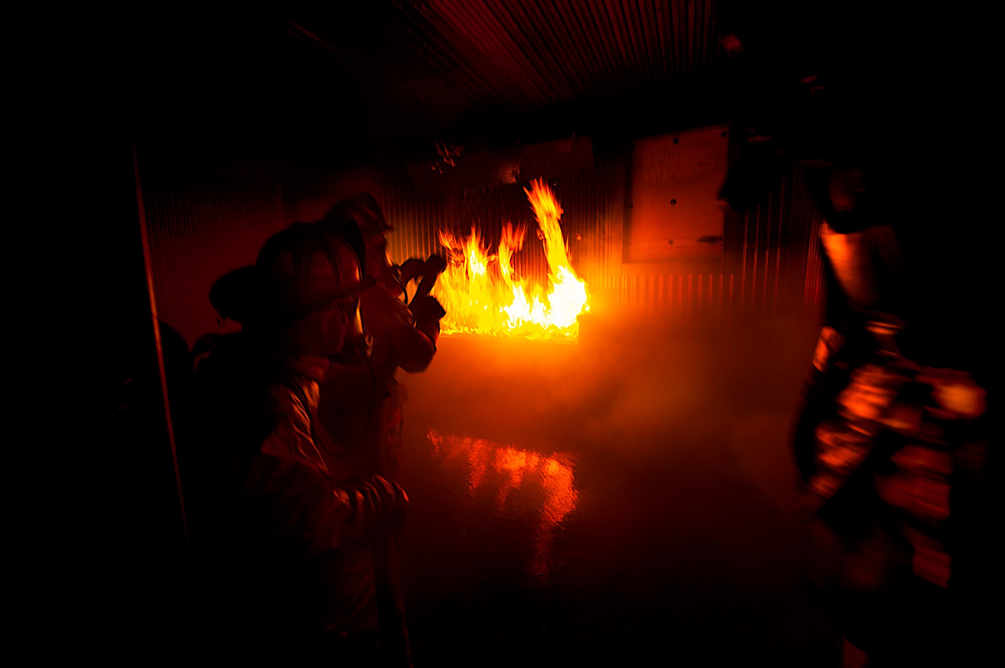 Firefighters from the 5th Civil Engineer Squadron participate in a controlled burn exercise at Minot Air Force Base, N.D., May 21, 2014. The fire training facility provides realistic training for the fire fighters with controlled flames emanating from specific areas of the building, and can be used in any type of weather to increase readiness of base and local community firefighters. (U.S. Air Force photo/Senior Airman Brittany Y. Bateman)
