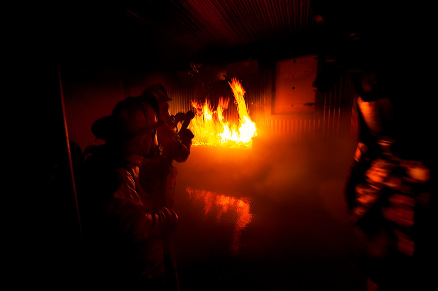 Firefighters from the 5th Civil Engineer Squadron participate in a controlled burn exercise at Minot Air Force Base, N.D., May 21, 2014. The fire training facility provides realistic training for the fire fighters with controlled flames emanating from specific areas of the building, and can be used in any type of weather to increase readiness of base and local community firefighters. (U.S. Air Force photo/Senior Airman Brittany Y. Bateman)