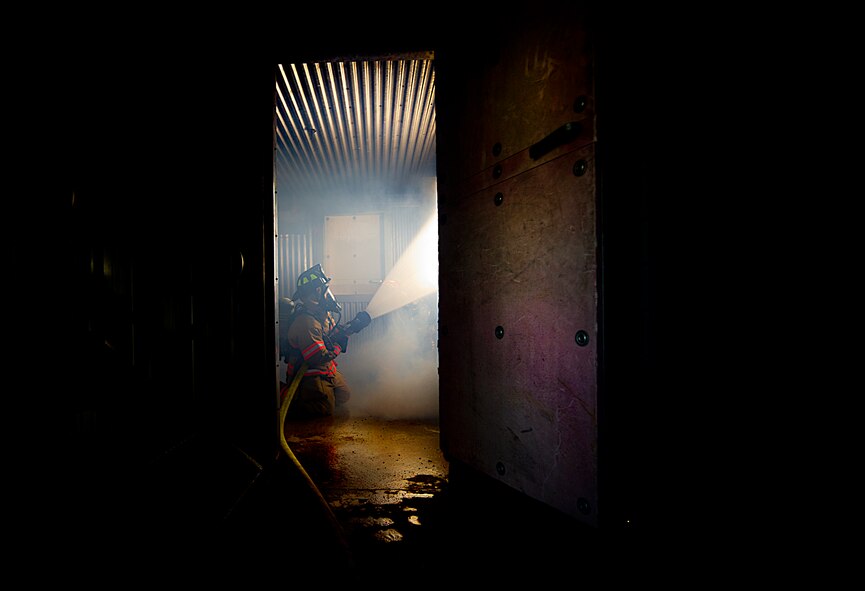 A fireman from the 5th Civil Engineer Squadron participates in a controlled burn exercise at Minot Air Force Base, N.D., May 21, 2014. The fire training facility provides realistic training for the fire fighters with controlled flames emanating from specific areas of the building, and can be used in any type of weather to increase readiness of base and local community firefighters. (U.S. Air Force photos/Senior Airman Brittany Y. Bateman)