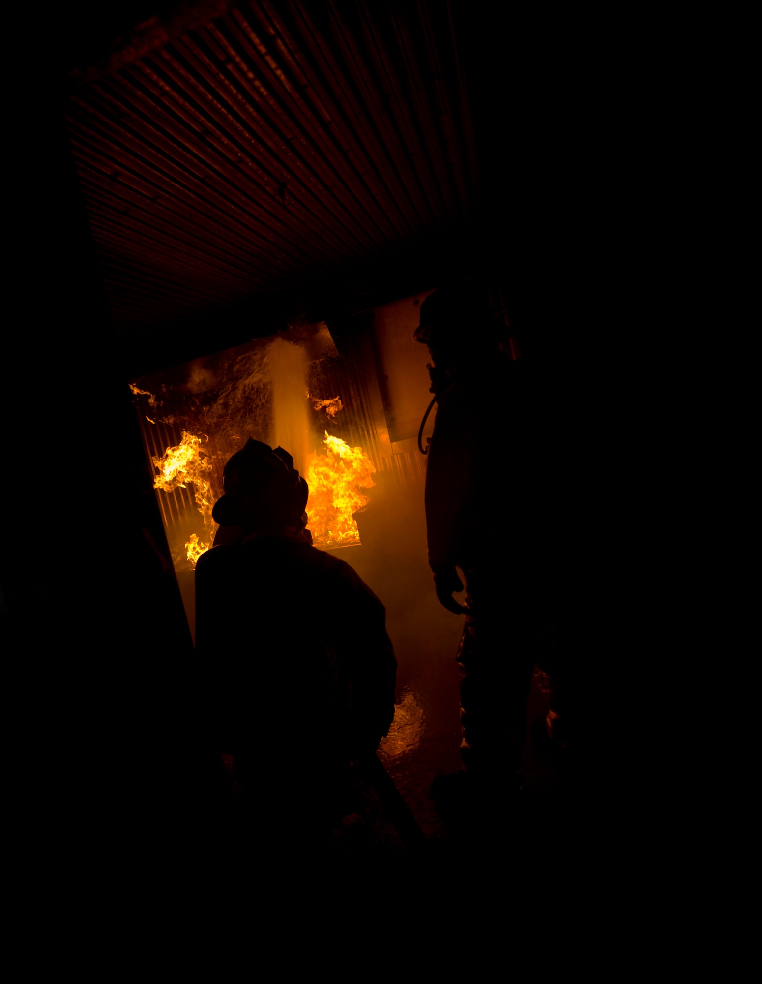 Firefighters from the 5th Civil Engineer Squadron participate in a controlled burn exercise at Minot Air Force Base, N.D., May 21, 2014. The multi-use structure provides an ability to train firefighters at all levels, from hose evolutions to command and control scenarios. It has movable walls to change room layout, and can test firefighter skills conducting search patterns and victim locating in blackout conditions. It provides opportunity for forcible entry training, confined space rescue, and offers realistic and scenario based sounds during training to add to the realism. (U.S. Air Force photo/Senior Airman Brittany Y. Bateman)