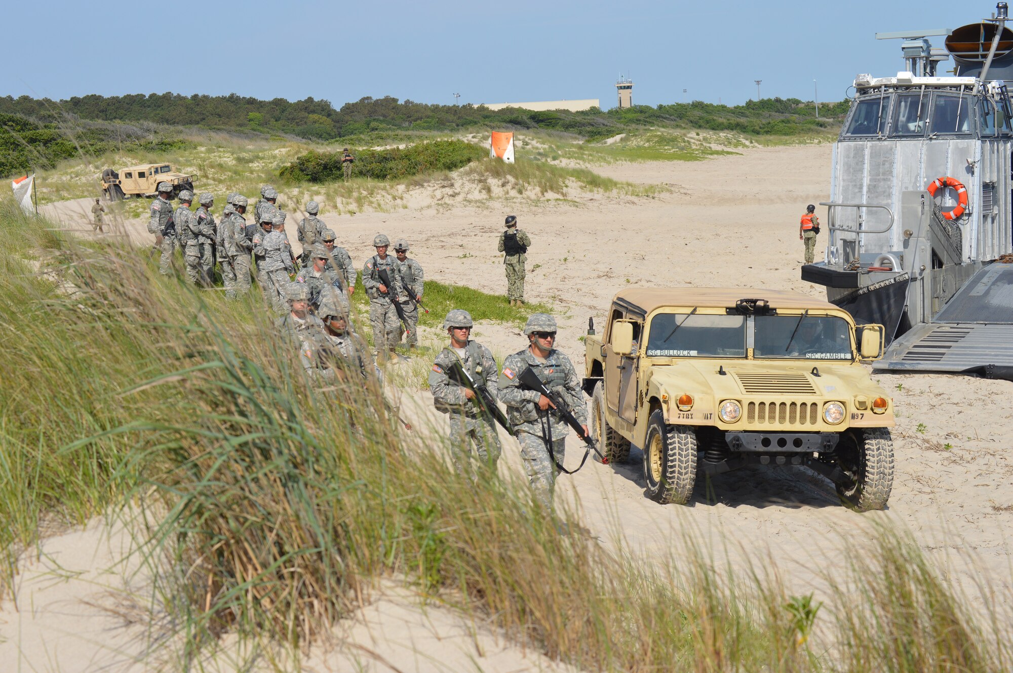 U.S. Army Soldiers from 11th Transportation Battalion, 7th Transportation Brigade (Expeditionary) prepare to storm the beach as part of a reenactment during the 70th Anniversary D-Day Remembrance Ceremony at Joint Expeditionary Base Little Creek-Fort Story, Va., June 6, 2014. Joint Expeditionary Base Little Creek-Fort Story was one of the bases used to help train Service members who went ashore on D-Day. (U.S. Army photo by Spc. Marian Alleva/Released) 