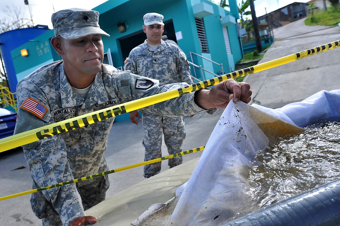 Army Spc. Luis Montalvo, foreground, demonstrates how a filter catches debris during training to purify water at the water utilities facility in San Lorenzo, Puerto Rico, May 31, 2014. Montalvo is a water treatment specialist assigned to the Puerto Rico Army National Guard's 714th Quartermaster Company, 191st Regional Support Group.