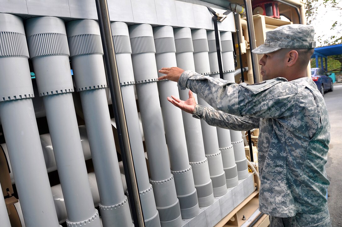 Army Spc. Luis Montalvo explains how water flows inside the cylinder filter during water purification training at the local water utilities facility in San Lorenzo, Puerto Rico, May 31, 2014. Montalvo is a water treatment specialist assigned to the Puerto Rico Army National Guard's 714th Quartermaster Company, 191st Regional Support Group.
