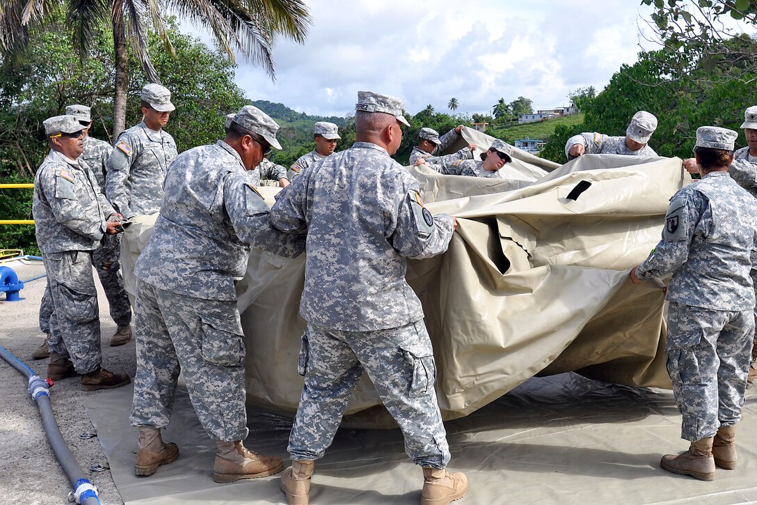 Soldiers spread out an empty 3,000-gallon onion tank before folding it for storage after learning to purify water at the water utilities facility in San Lorenzo, Puerto Rico, May 31, 2014.