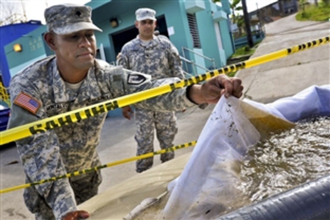 Army Spc. Luis Montalvo, foreground, demonstrates how a filter catches debris during training to purify water at the water utilities facility in San Lorenzo, Puerto Rico, May 31, 2014. Montalvo is a water treatment specialist assigned to the Puerto Rico Army National Guard's 714th Quartermaster Company, 191st Regional Support Group.