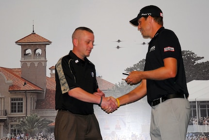 Professional golfer Nick Watney, right, presents a membership to The Players Championship in Boston to retired Rhode Island National Guard Sgt. Michael McCombs during Military Appreciation Day at TPC Sawgrass, Florida, May 9, 2012.The membership was presented to McCombs, an avid golfer who was medically retired in 2005, in honor of his service in the military.