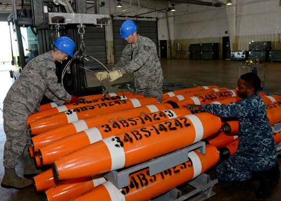 Staff Sgt. Raymond Elmendorf and Airman 1st Class Eric Morrison assist Petty Officer 2nd Class Dwight Moore with loading Mk-62 Quickstrike mines onto munitions carts June 2, 2014, at Ellsworth Air Force Base, S.D. Elmendorf and Morrison are 28th Munitions Squadron conventional maintenance crew members. Moore is a Naval Munitions Command Seal Beach mineman. (Air Force photo/Senior Airman Anania Tedurio)