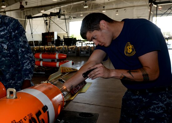 Petty Officer 2nd Class Daniel Bentley adjusts the fin assembly on an Mk-62 Quickstrike mine June 2, 2014, at Ellsworth Air Force Base, S.D. The B-1B Lancer pilots dropped the mines at an altitude of about 1,000 feet while moving at more than 500 kilometers an hour as part of a joint exercise with Ellsworth AFB Airmen designed to enhance air and sea capabilities. Bentley is a Naval Munitions Command Charleston mineman, (U.S. Air Force photo by Senior Airman Anania Tekurio)