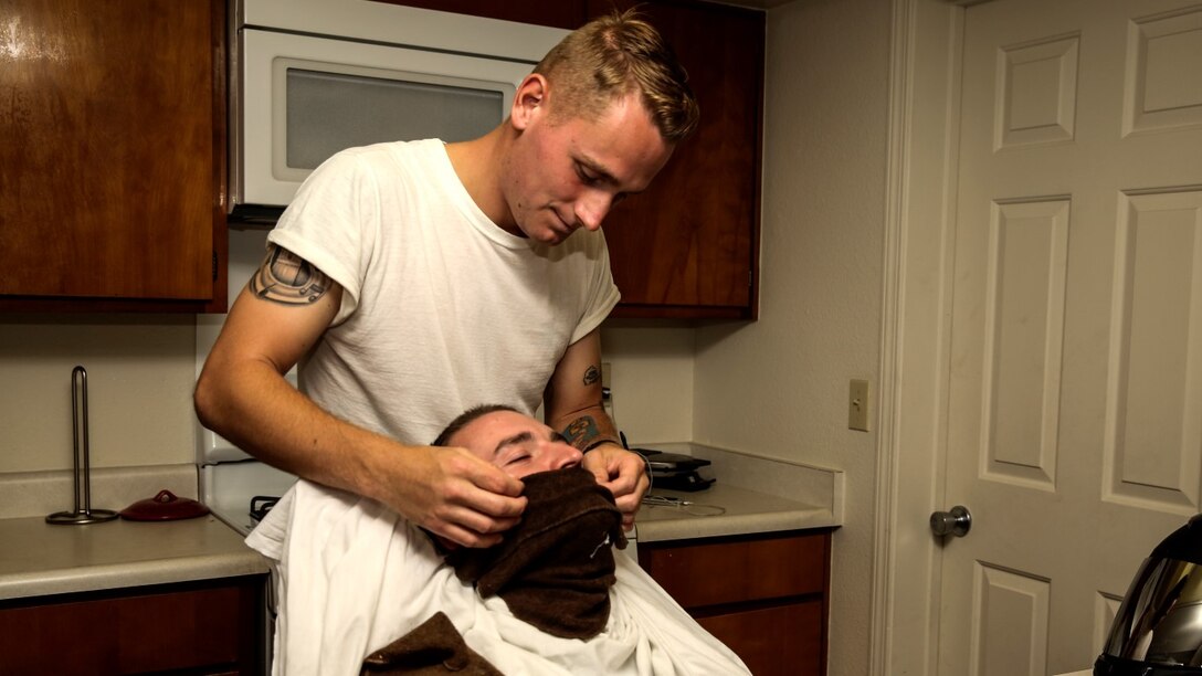 Corporal Carl Provost, automotive mechanic, 15th Marine Expeditionary Unit prepares to shave Lance Cpl. Lukasz Wlodkowski, automotive maintenance technician, Combat Logistics Battalion 5, at his home aboard Camp Pendleton, Calif. June 8, 2014. Provost is from Duluth, Minn. (U.S. Marine Corps photo by Lance Cpl. Anna Albrecht/Released)