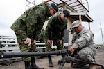 Army Sgt. Wichai Johnson, a member of the 1404th Transportation Company, from the Arizona Army National Guard, demonstrates how to operate an M2 .50-caliber machine gun for two officer members of the Canadian Army reserve at the Orchard Combat Training Area, Boise, Idaho May 3, 2012. Operation Cougar Salvo 12 was a joint- multinational exercise, held April 23, 2012 to May 5, 2012, for NATO allies from the U.S. and Canada to practice combat support and sustainment exercises.