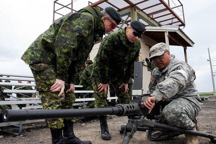 Army Sgt. Wichai Johnson, a member of the 1404th Transportation Company, from the Arizona Army National Guard, demonstrates how to operate an M2 .50-caliber machine gun for two officer members of the Canadian Army reserve at the Orchard Combat Training Area, Boise, Idaho May 3, 2012. Operation Cougar Salvo 12 was a joint- multinational exercise, held April 23, 2012 to May 5, 2012, for NATO allies from the U.S. and Canada to practice combat support and sustainment exercises.