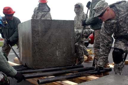 New York Army National Guard Sgt. John Grace, member of the 1156th Engineer Company's Search and Extraction Team, places a roller in front of a two-ton block as it moves 75 feet past obstacles at the New York State Preparedness Center, May 14, 2012. The exercise helped train Soldiers to rescue civilians from collapsed buildings and is one component of Homeland Response Force validation training for supporting civil authorities in the event of a national disaster.