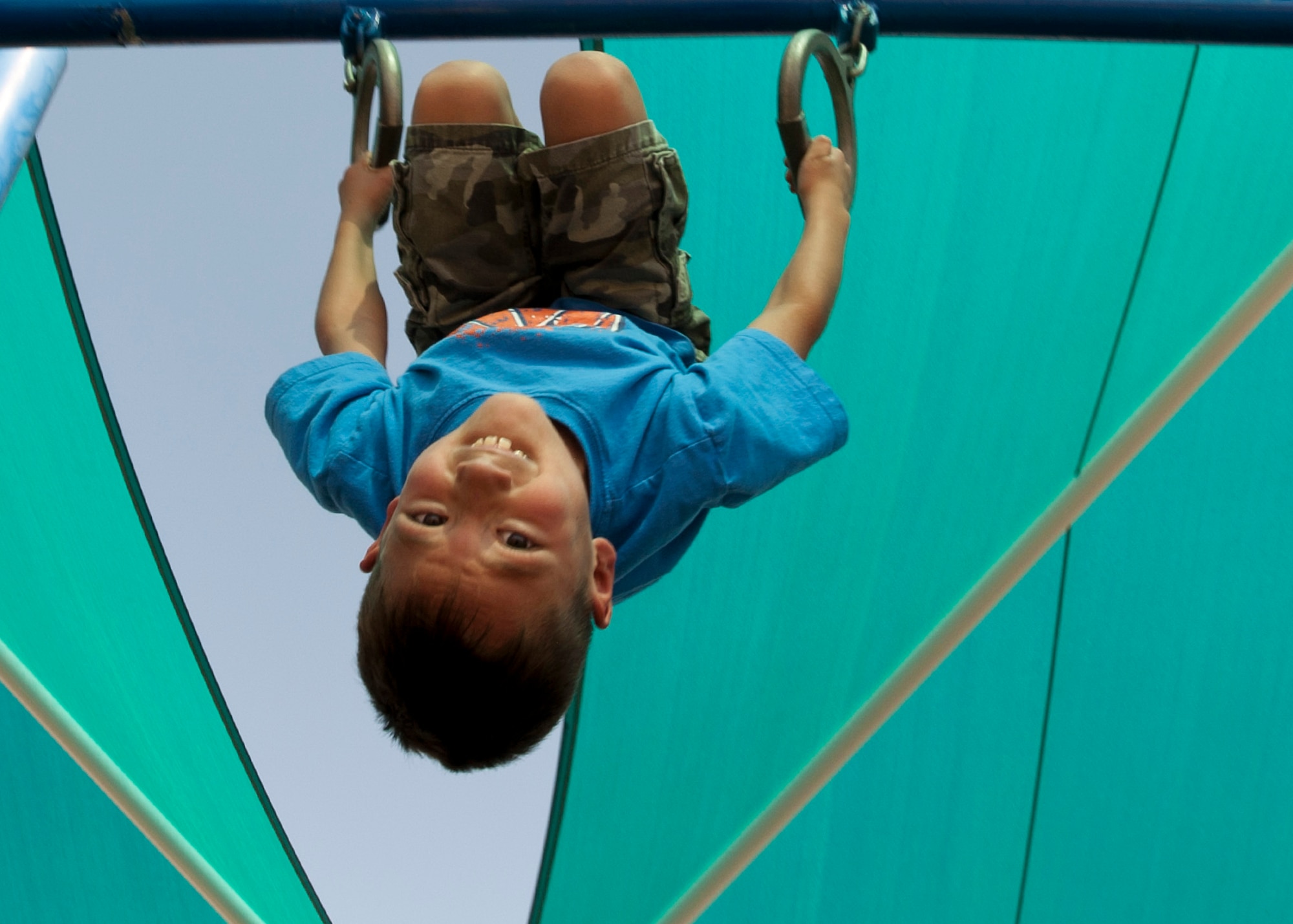 Anthony hangs upside-down on monkey rings on the playground of the 99th Force Support Squadron Youth Center June 5, 2014, at Nellis Air Force Base, Nev. The youth center’s playground is used in promoting exercise through play. (U.S. Air Force photo by Senior Airman Timothy Young)