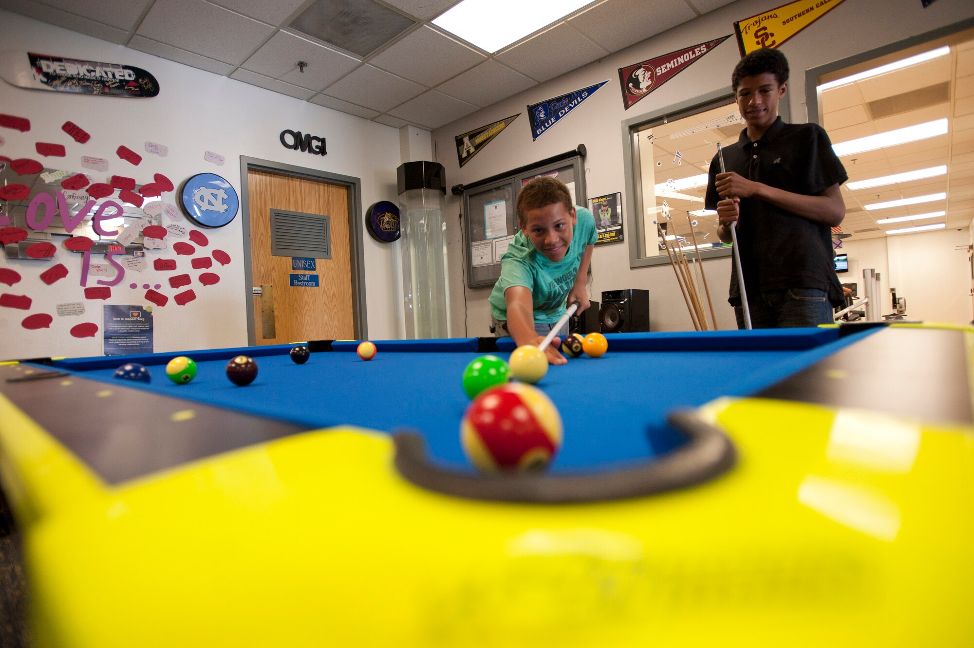 Thomas lines up a shot as Marcus watches during a billiard game at the 99th Force Support Squadron Youth Center June 5, 2014, Nellis Air Force Base, Nev. The youth center has two billiard tables available for use to children and teens. (U.S. Air Force photo by Senior Airman Timothy Young)