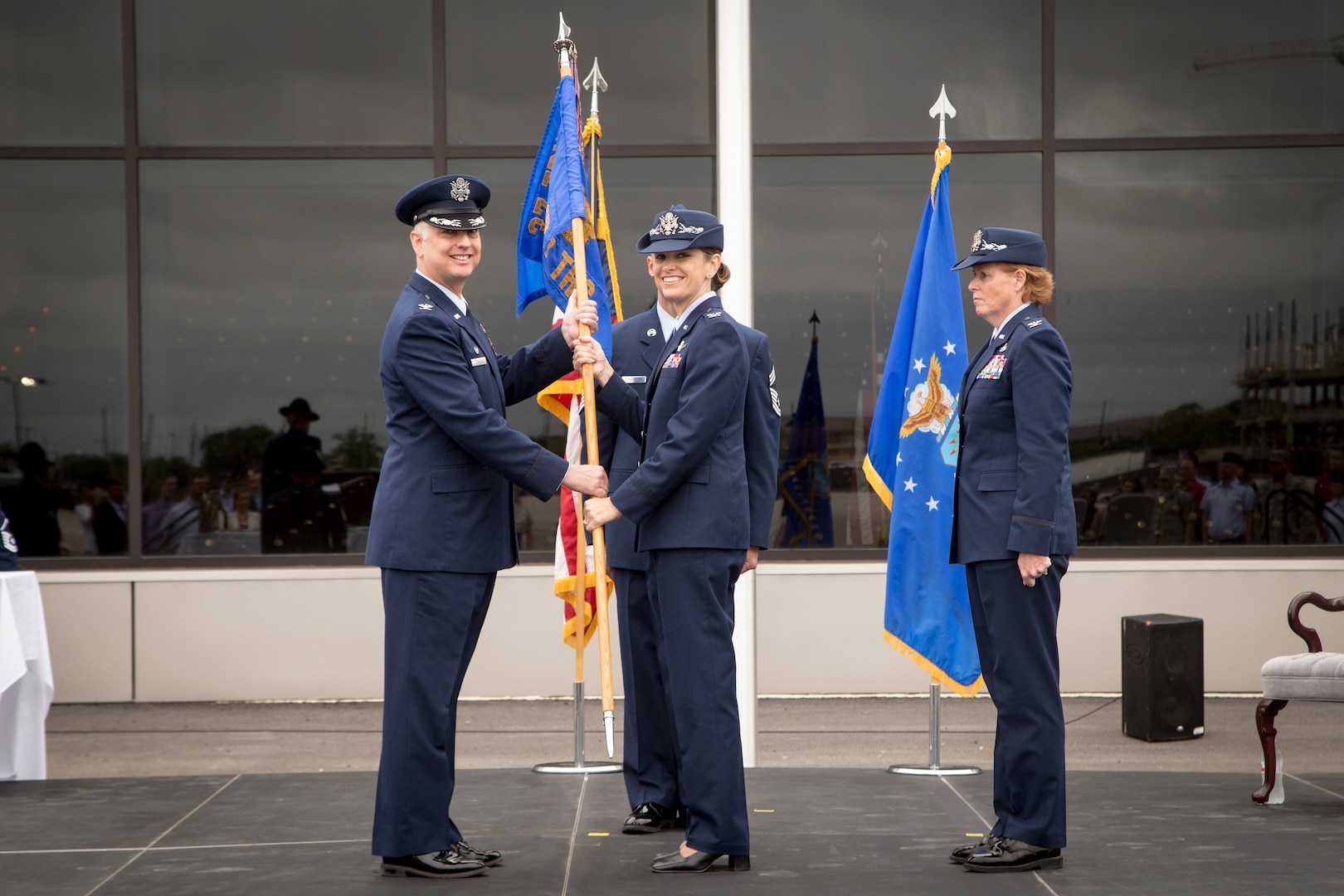 Col. Mark Camerer (left), 37th Training Wing commander, passes the 737th Training
Group guidon to Col. Michele Edmondson during a change of command ceremony Monday. Edmondson replaces Col. Deborah Liddick (right) as BMT commander. (U.S. Air Force Photo by Joshua Rodriguez)