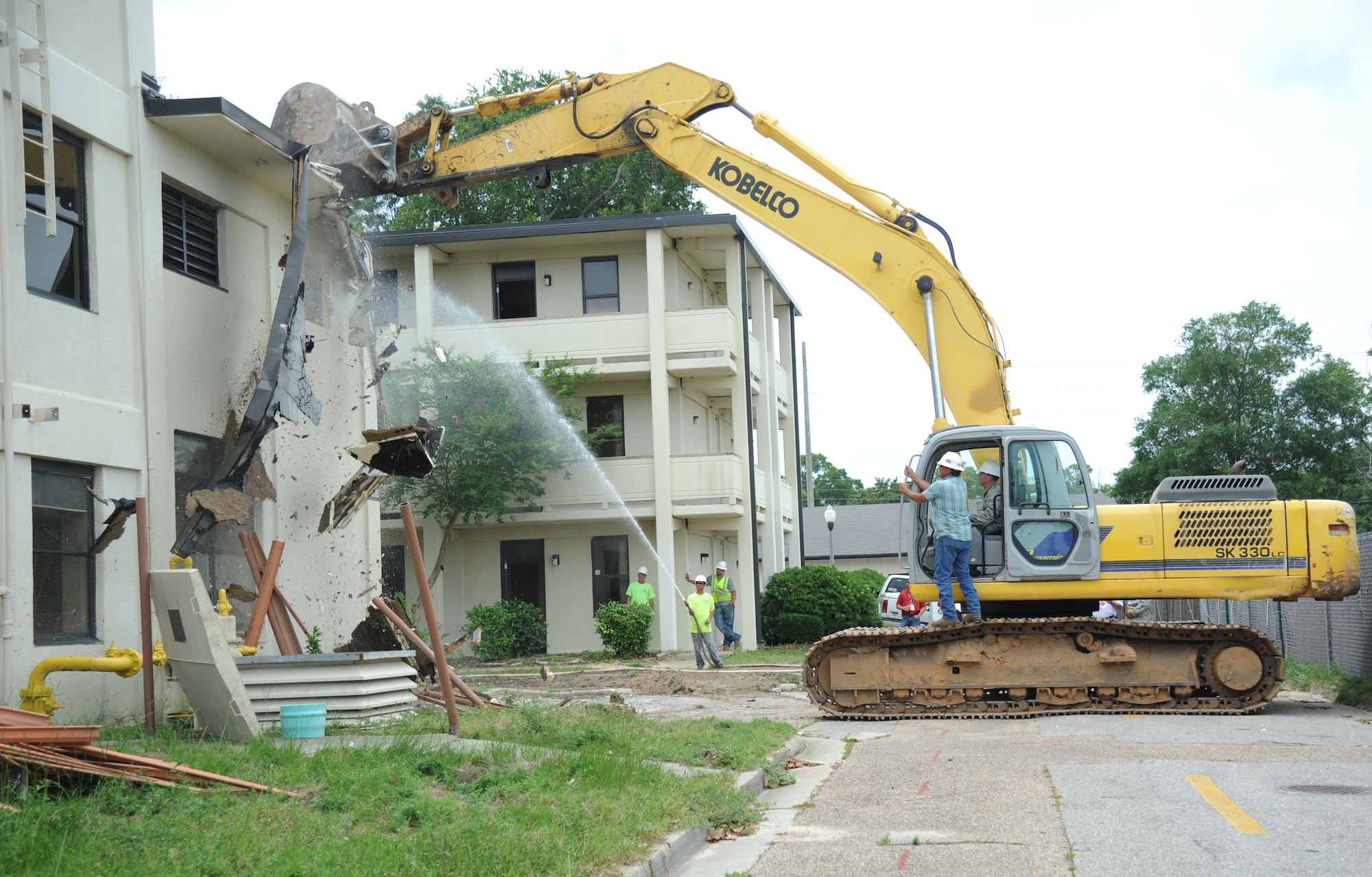 Jeff Smith, Base Operations Support contractor, shows Brig. Gen. Patrick Higby, 81st Training Wing commander, how to operate an excavator as he begins the demolishing of building 4815 June 10, 2014, at Keesler Air Force Base, Miss.  The demolishing of Building 4815 will be continued by Business Integrity Commission, the prime demolishing contractor, as well as building 4813. (U.S. Air Force photo by Kemberly Groue)