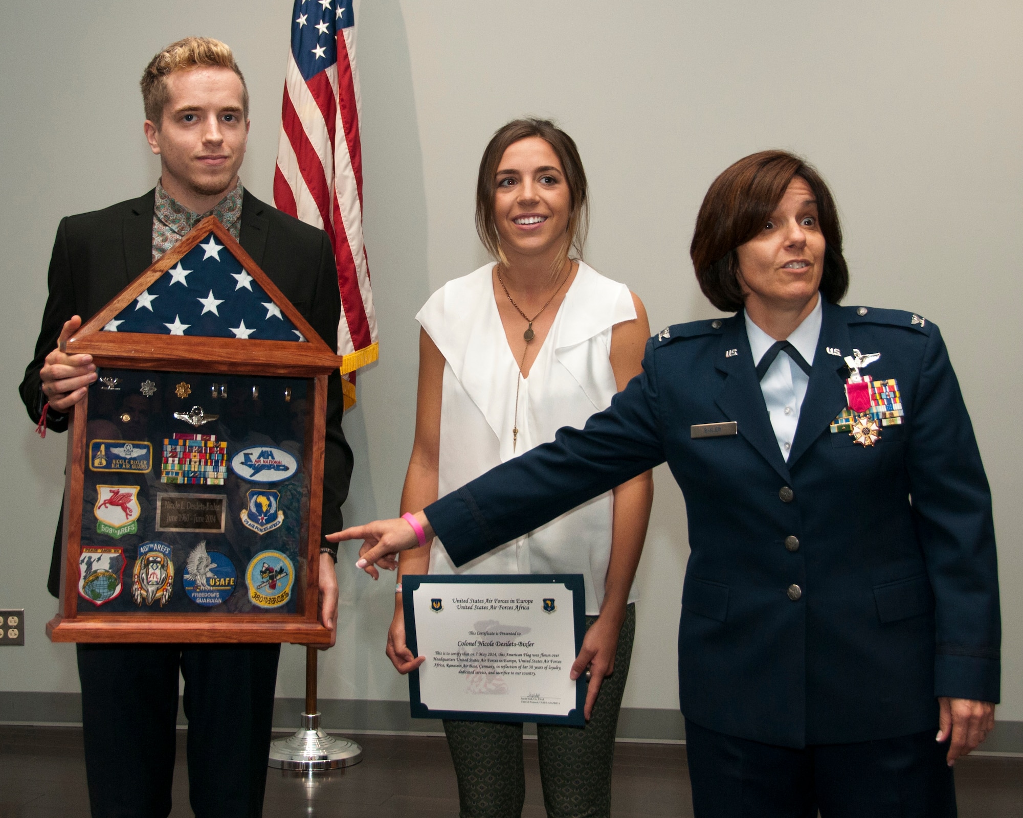 PEASE AIR NATIONAL GUARD BASE, N.H—Col. Nicole L. Desilets-Bixler  speaks about her shadow box that she was presented during her  during her retirement ceremony in building 264, on June 8, 2014. Bixler retires after 34 years of service and she has the distinction of being on the first N.H. Guard all-female flight crew which flew veterans to the Woman's memorial in Washington D.C. for its dedication. Her children, Robbie and Genevieve look on. (U.S. Air National Guard photo by Staff Sgt. Curtis J. Lenz) 