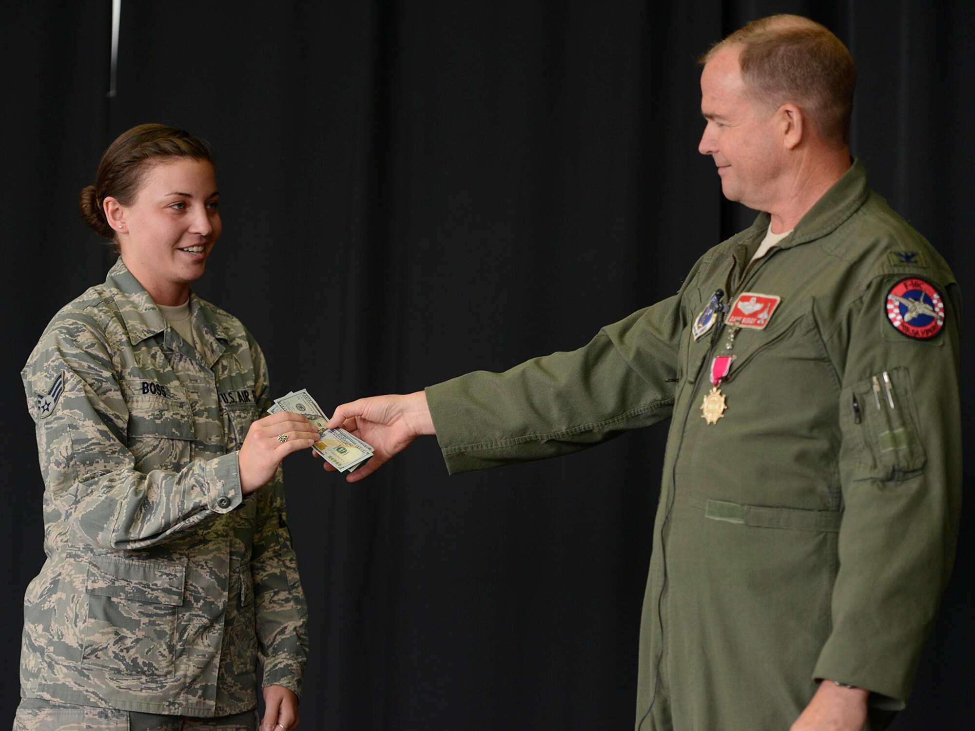During a Commanders Call at the Tulsa Air National Guard base, June 8, 2014.  Colonel David B. Burgy, 138th Fighter Wing Commander,  presents two, one hundred dollar bills to Senior Airman Hannah Boss for her recruiting efforts.   Burgy regularly issues the recruiting challenge to members of the 138th and includes the monetary award as incentive.   (U.S. National Guard photo by Master Sgt.  Mark A. Moore/Released)
