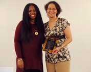Senior Airman Charnell Burroughs (left), 319th Comptroller Squadron commander’s support staff, presents a service award to Sonia L. Brumskill, 319th Civil Engineer Squadron service contract evaluator, on Feb. 28, 2014 on Grand Forks Air Force Base, N.D. The service award recognized the body of work Brumskill has done on base with the volunteer community and the African American Cultural Association since 2002. (Air Force photo/Senior Airman Zachiah Roberson)