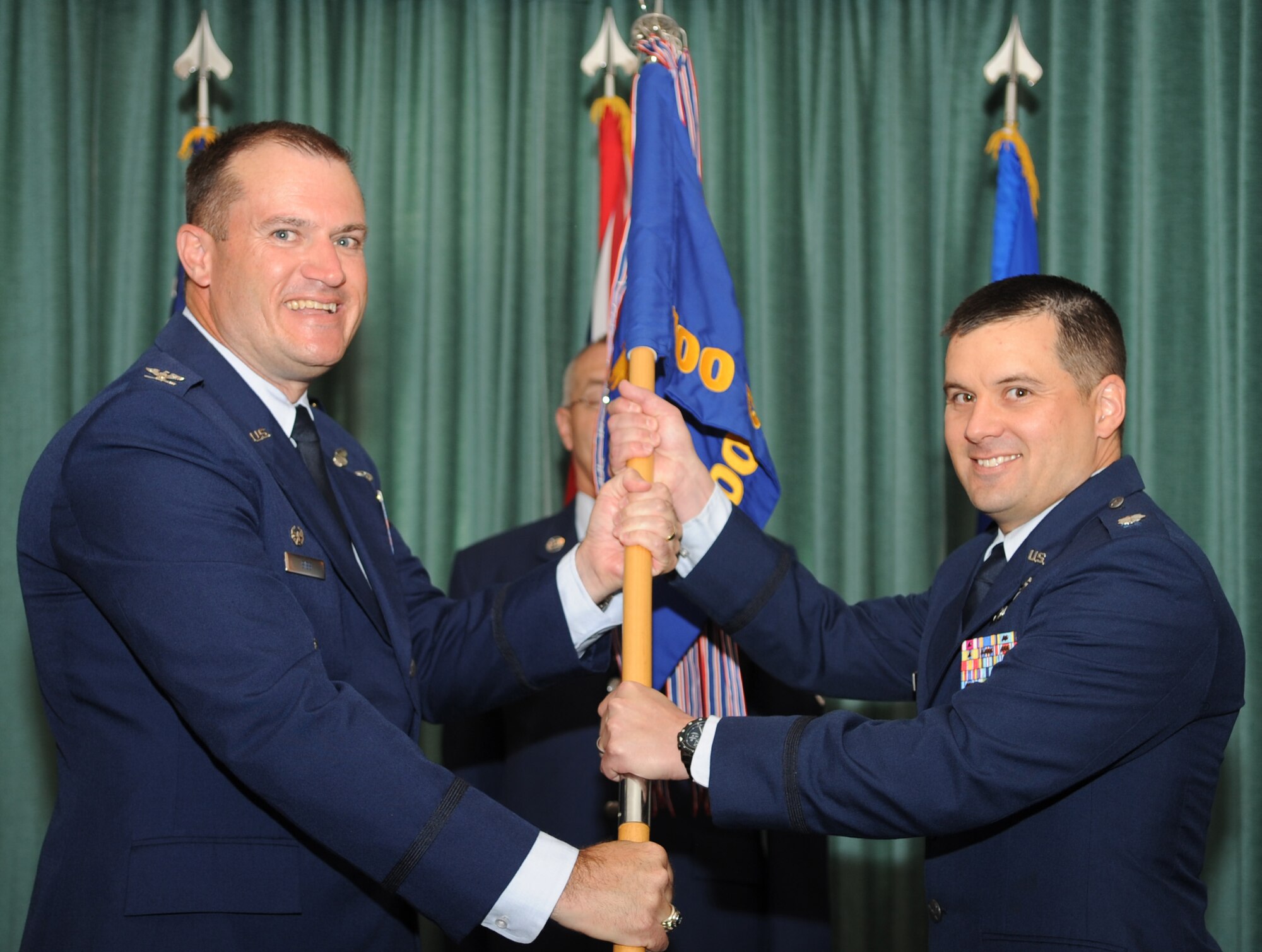 U.S. Air Force Col. Kenneth T. Bibb Jr., left, 100th Air Refueling Wing commander, passes the guidon to U.S. Air Force Lt. Col. Jason Holcomb, incoming  100th Comptroller Squadron commander, during the 100th CPTS change of command ceremony June 10, 2014, in Middleton Hall on RAF Mildenhall, England. Holcomb previously served as the Budget Integration Team chief as part of the Financial Management Leadership program at Headquarters Air Mobility Command, Scott Air Force Base, Ill. U.S. Air Force Lt. Col. Charles Barkhurst relinquished command of the squadron to Holcomb. (U.S. Air Force photo/Airman 1st Class Dillon Johnston/Released)