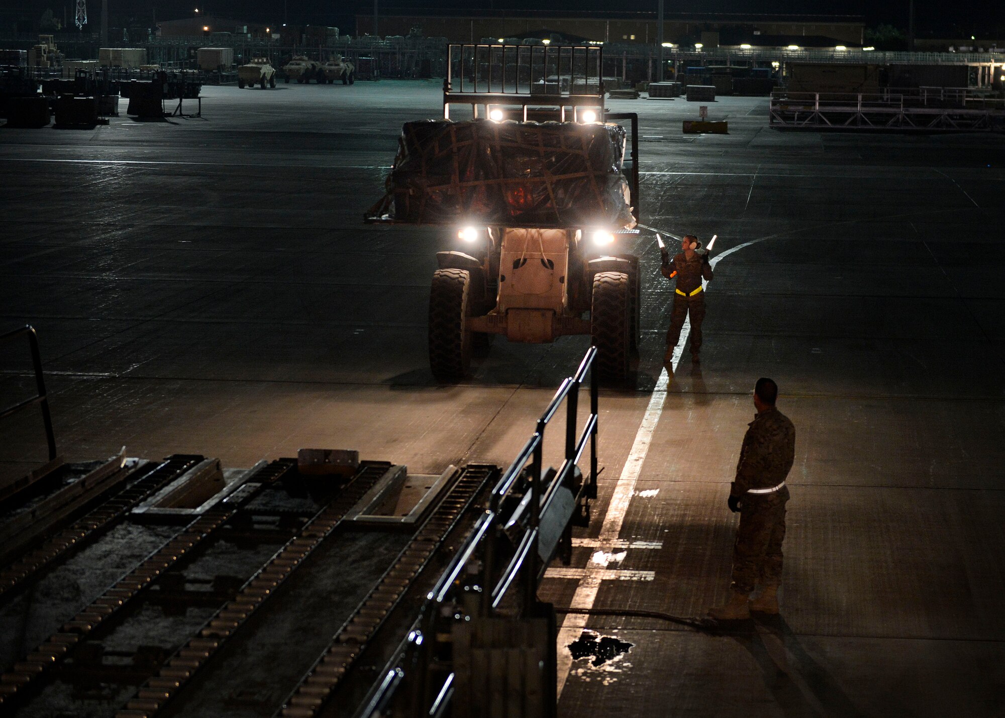 (From left) U.S. Air Force Airman 1st Class Kayla Murray, 455th Expeditionary Aerial Port Squadron aerial porter and Senior Airman Michael Kowalski, 455 EAPS aerial porter, guide a forklift to a C-5 Galaxy aircraft at Bagram Airfield, Afghanistan May 26, 2014.  The squadron services an average of 1,300 aircraft, 12, 000 tons of cargo and 9,000 passengers per month.  Murray is deployed from Yokota Air Base, Japan and a native of De Soto, Miss.  Kowalski is deployed from Niagara Falls Air Reserve Station, N.Y. (U.S. Air Force photo by Staff Sgt. Evelyn Chavez/Released)