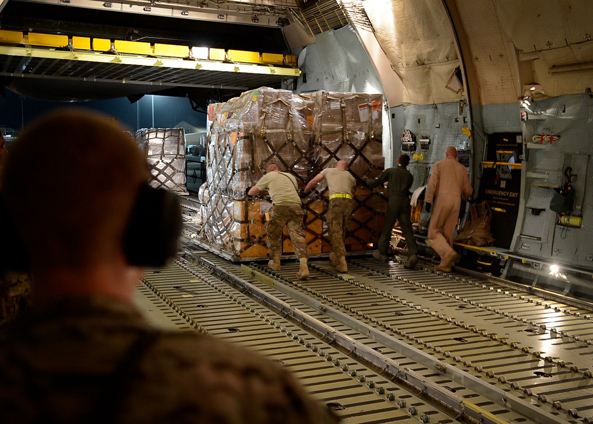 U.S. Air Force Airmen from the 455th Expeditionary Aerial Port Squadron push cargo from a C-5 Galaxy aircraft at Bagram Airfield, Afghanistan May 26, 2014.  The squadron services an average of 1,300 aircraft, 12, 000 tons of cargo and 9,000 passengers per month. (U.S. Air Force photo by Staff Sgt. Evelyn Chavez/Released)