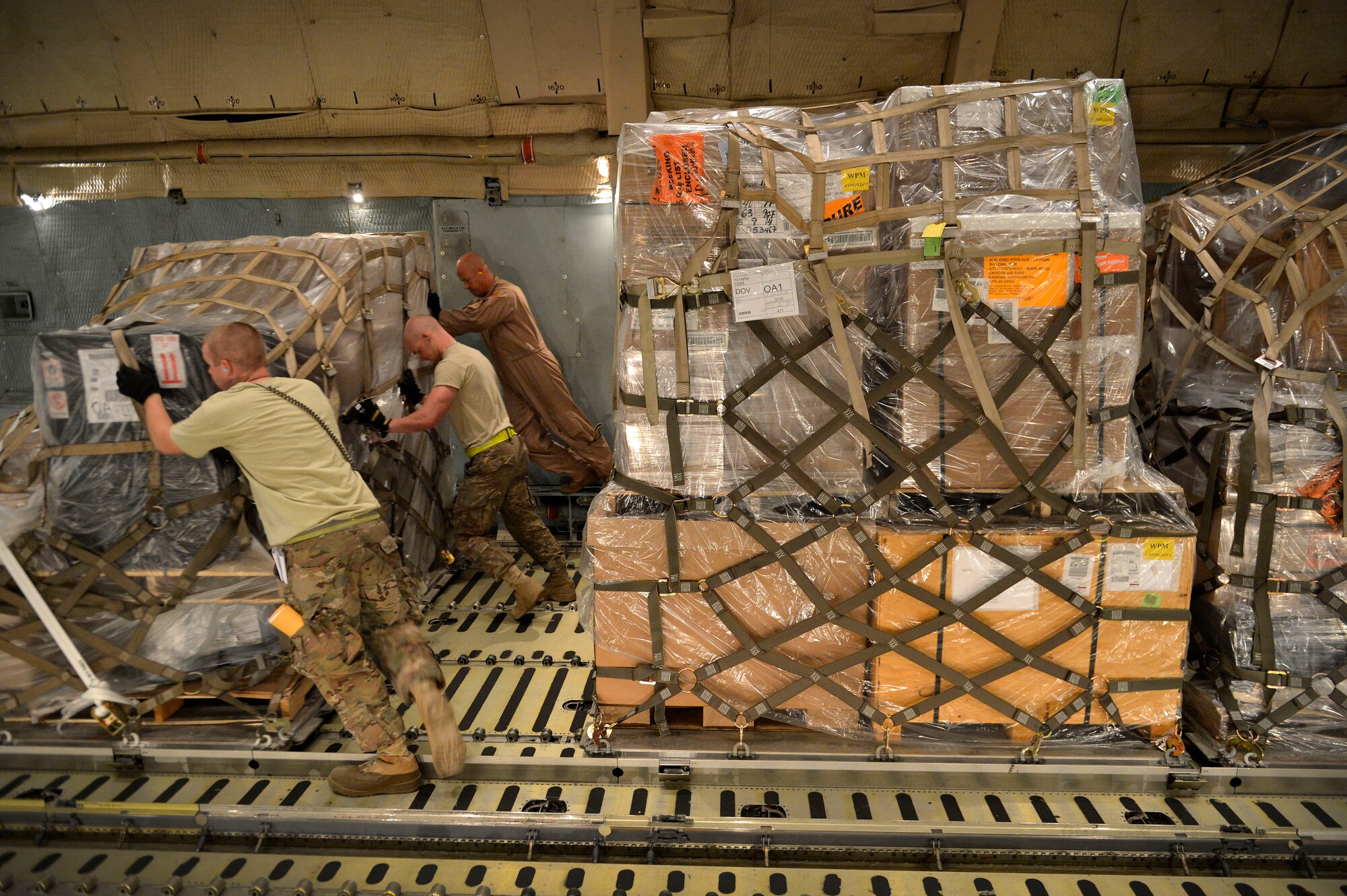 A U.S. Air Force Airmen from the 455th Expeditionary Aerial Port Squadron push cargo from a C-5 Galaxy aircraft at Bagram Airfield, Afghanistan May 26, 2014.  The squadron services an average of 1,300 aircraft, 12, 000 tons of cargo and 9,000 passengers per month. (U.S. Air Force photo by Staff Sgt. Evelyn Chavez/Released)