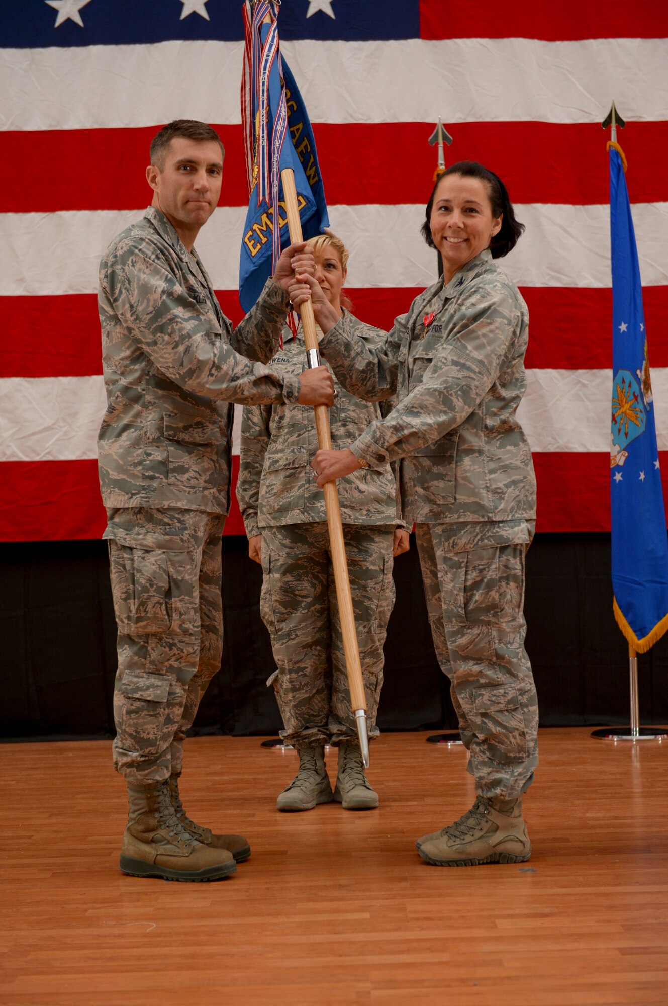 Col. Jeannine Ryder, 386th Expeditionary Medical Group commander, passes the 386th EMDG guidon to Col. John Klein, 386th Air Expeditionary Wing commander during a change of command ceremony held June 8, 2014 at The Rock. Ryder relinquished command of the 386th EMDG to Col. Susan Davis who deployed from the 59th Medical Wing, Joint Base San Antonio-Lackland, Texas. (U.S. Air Force photo by Staff Sgt. Jeremy Bowcock)