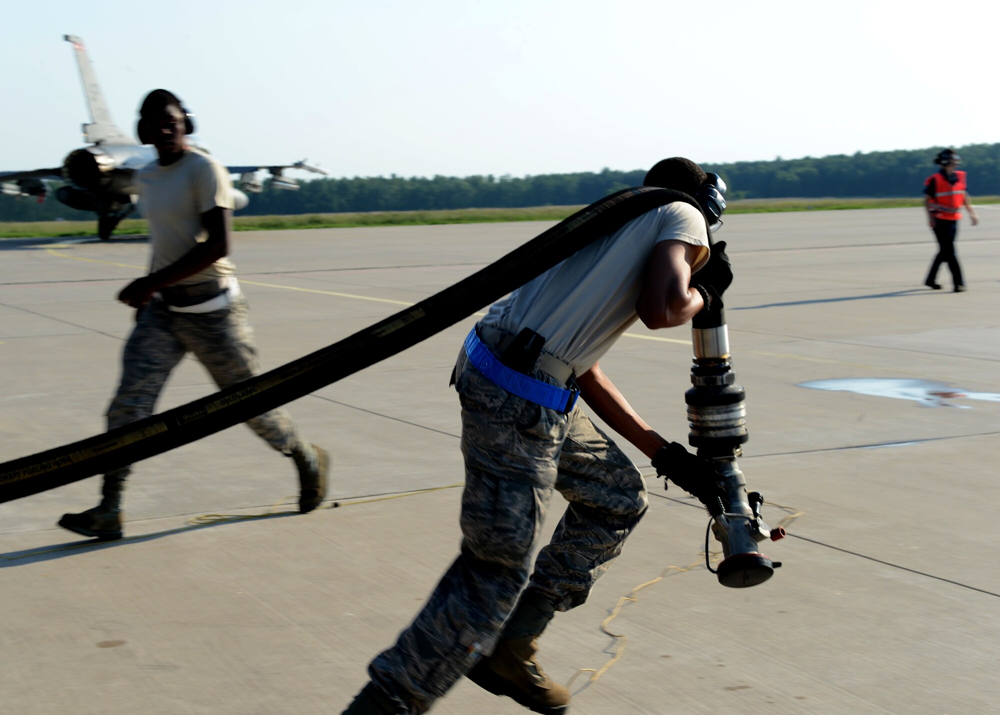 U.S. Air Force Staff Sgt. Jemarco Brooks, 52nd Logistics Readiness Squadron fuels distribution operator, runs a fuel hose out to refuel a returning U.S. Air Force F-16 Fighting Falcon fighter aircraft at Lask Air Base, Poland, June9, 2014. This is the first time hot pit refueling has been done in Poland by U.S. Forces. U.S. Aviation Detachment Rotation 14-3 supported Exercise EAGLE TALON and BALTOPS 14 by providing a rotation of 18 F-16 aircraft to train with NATO partners. The continuous presence in Eastern Europe aims to reassure NATO allies and maintain security in the region. (U.S. Air Force photo by Airman 1st Class Kyle Gese/Released)