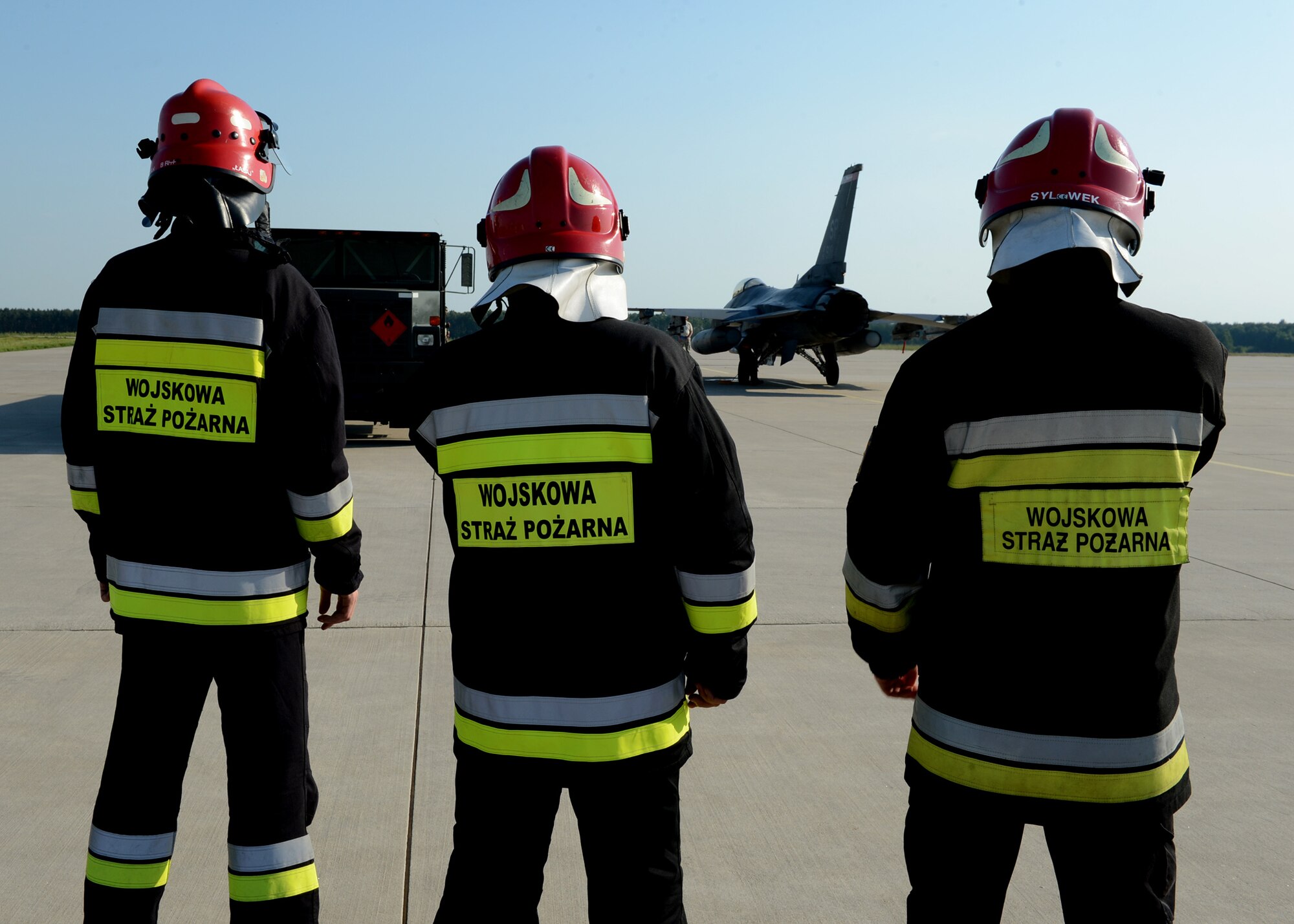 Polish fire rescue men stand watch over U.S. Air Force F-16 Fighting Falcon fighter aircraft refueling operations at a hot refueling pit at Lask Air Base, Poland, June 9, 2014. During Polish-led EAGLE TALON and U.S. Navy-led BALTOPS 14, NATO allies worked together to increase interoperability and mission effectiveness while maintaining security in Eastern Europe.This is the first time hot pit refueling has been done in Poland by U.S. Forces. (U.S. Air Force photo by Airman 1st Class Kyle Gese/Released)