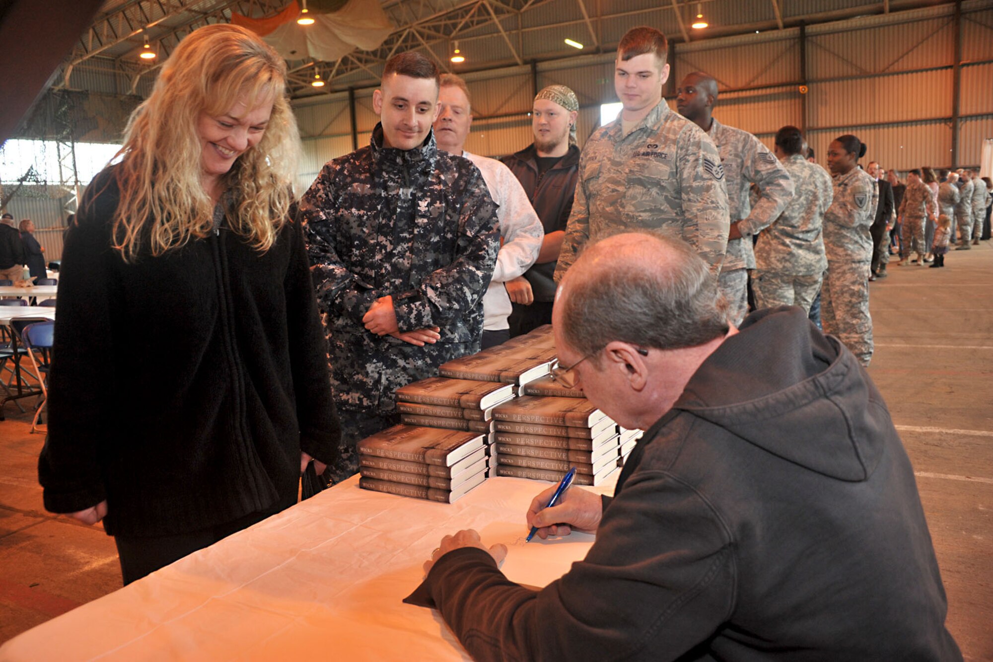 Dr. Robert J. Wicks, psychologist, motivational speaker and author, signs his latest book for RAF Molesworth personnel and their families during Resiliency Day in hangar 92 at RAF Molesworth, United Kingdom May 30, 2014. Wicks has published more than 50 books and traveled the world to help people become more resilient in life. (U.S. Air Force photo by Staff Sgt. Ashley Hawkins/Released)