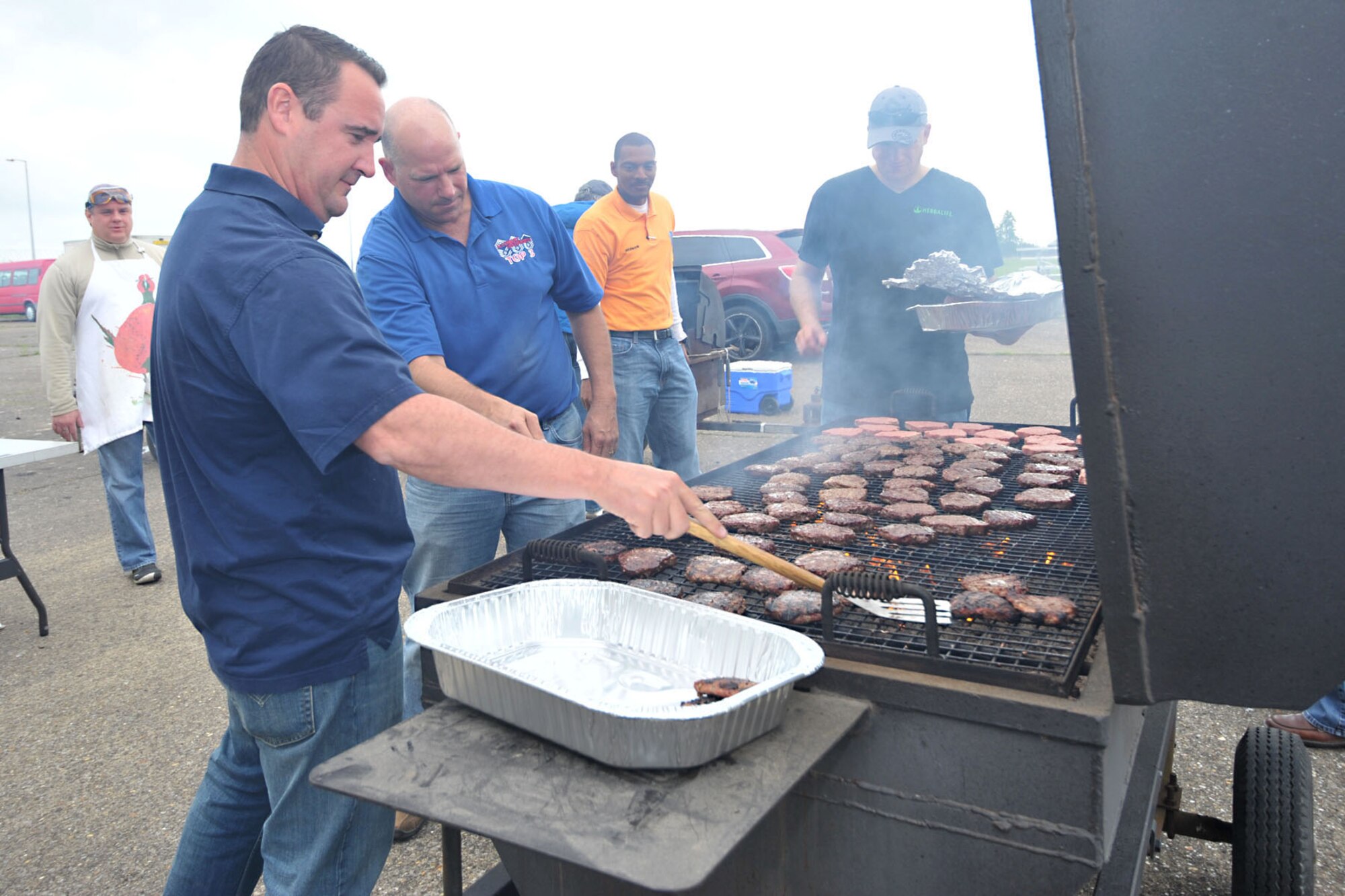 U.S. Africa Command personnel grill burgers during Resiliency Day at hangar 92 at RAF Molesworth, United Kingdom May 30, 2014. USAFRICOM personnel combined their annual spring fling with the 423rd Chaplain’s Office’s Resiliency Day to provide personnel relief from the stressors of work, an opportunity to spend more time with their families as well as offer motivation to stay flexible throughout life. (U.S. Air Force photo by Staff Sgt. Ashley Hawkins/Released)