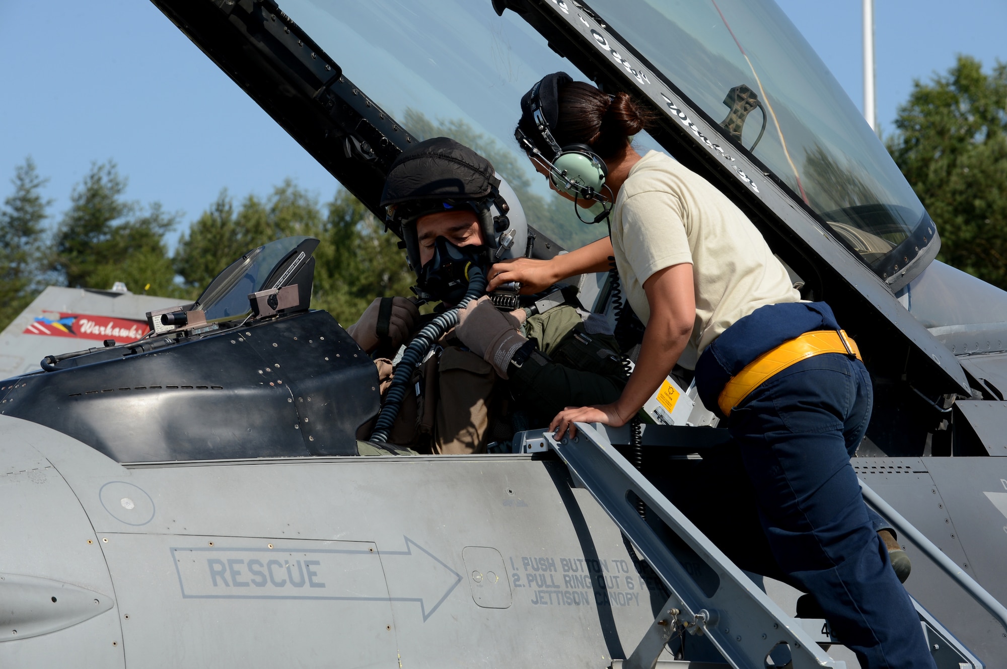 U.S. Air Force Senior Airman Kimberly Szydlowski, a 52nd Aircraft Maintenance Squadron F-16 Fighting Falcon fighter aircraft crew chief from St. Louis, straps in U.S. Air Force Maj. Nathanael Karrs, a 480th Fighter Squadron F-16 pilot from Rocky Mount, N.C., at Lask Air Base, Poland, June 9, 2014. Karrs trained with NATO partners from the United Kingdom, France and Poland in the Polish-led exercise EAGLE TALON. Exercises such as these help develop and improve a ready air force between NATO partners for future operations. (U.S. Air Force photo by Airman 1st Class Kyle Gese/Released)