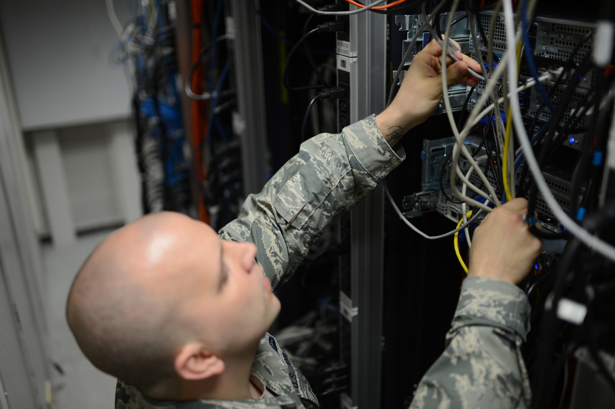 U.S. Air Force Senior Airman Edward Bodenheimer, 52nd Communications Squadron cyber system operations technician from Lumberton, N.C., adjusts cables in a server room at Spangdahlem Air Base, Germany, June 10, 2014. Once a month, Airmen conduct a full walkthrough inspection of the server room to ensure all cables are plugged in correctly and serviceable. (U.S. Air Force photo by Senior Airman Gustavo Castillo/Released)
