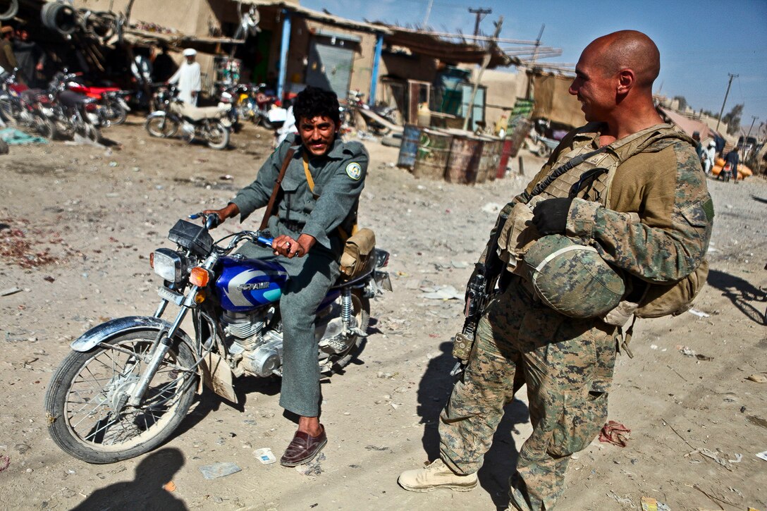 U.S. Marine Sgt. Chris Gonzalez speaks with a member of the Afghan police at the Kajaki Sofla Bazaar in Helmand province, Afghanistan, Nov. 5, 2011. Gonzalez is the civil affairs team chief assigned to Company B, 1st Battalion, 6th Marine Regiment. U.S. Marines joined Afghan police to celebrate the Islamic holiday of Eid al-Adha, which encourages reconciliation and charitable giving.  
