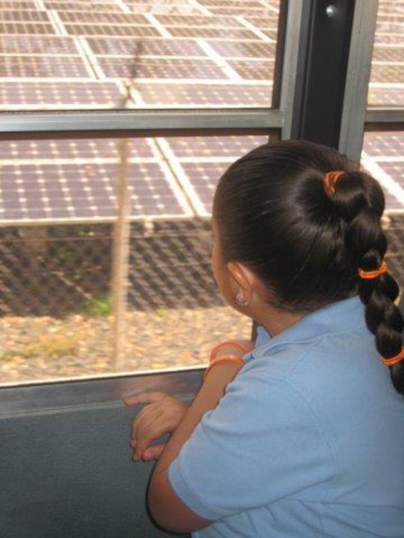 As her school bus arrives at a project site at Fort Buchanan, Puerto Rico, a first grade student from Antilles Elementary School views the solar panels that were installed by Fort Buchanan’s Environmental Division as an alternative energy source. 

