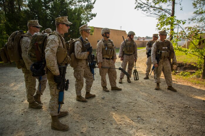 Marines with Alpha Company, 8th Engineer Support Battalion, 2nd Marine Logistics Group and Explosive Ordnance Disposal Marines discuss the procedures of improvised explosive device detection and clearing during a Military Operations in Urban Terrain exercise aboard Camp Lejeune, N.C., June 5, 2014. Marines with the unit encountered a simulated improvised explosive device during a patrol and utilized Explosive Ordnance Disposal Marines to clear the road before continuing into an artificial town to continue MOUT training. 