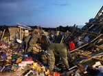As the sun comes up in Joplin, Mo., on May 23, 2011, the Missouri National Guard's 117th Engineer Team's search and rescue specialists sort through rubble left by a tornado that roared into Jasper County Sunday evening.